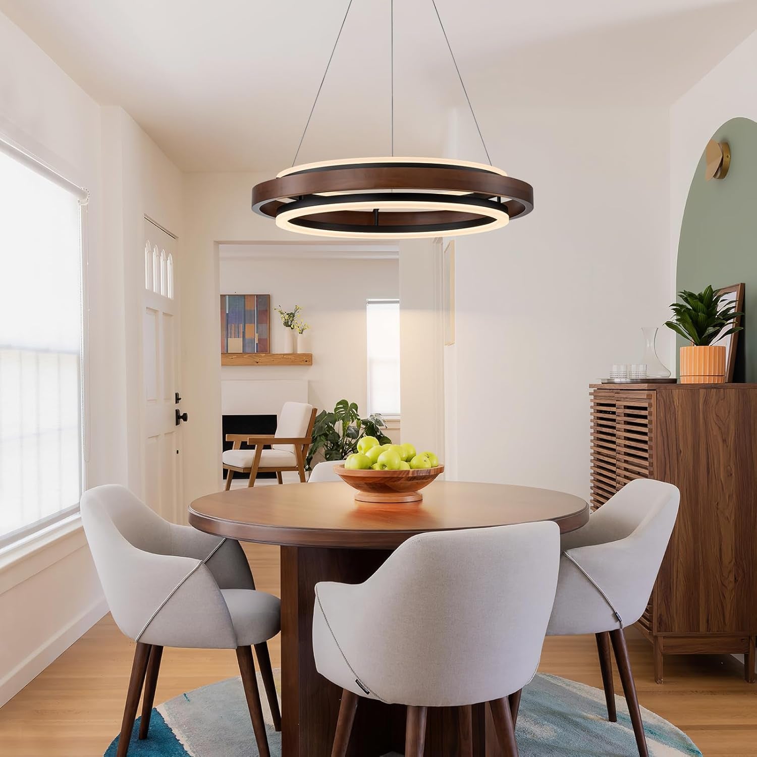 Walnut-color two-ring LED round chandelier hanging above a round dining table in a bright dining room