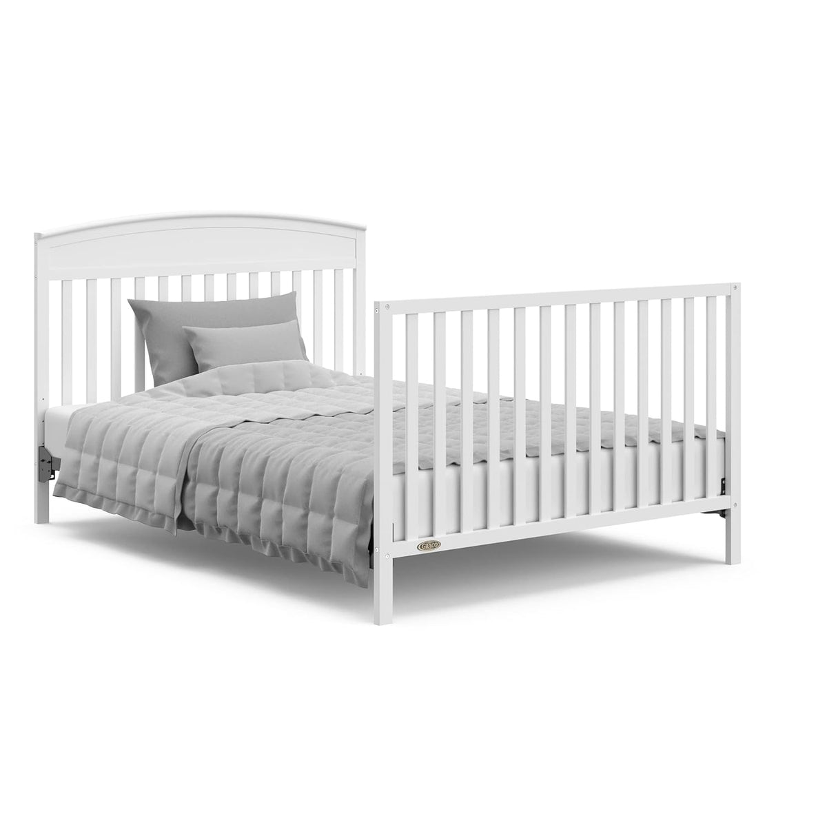 Angled view of the crib converted into a full-size bed with headboard, footboard and bedding.