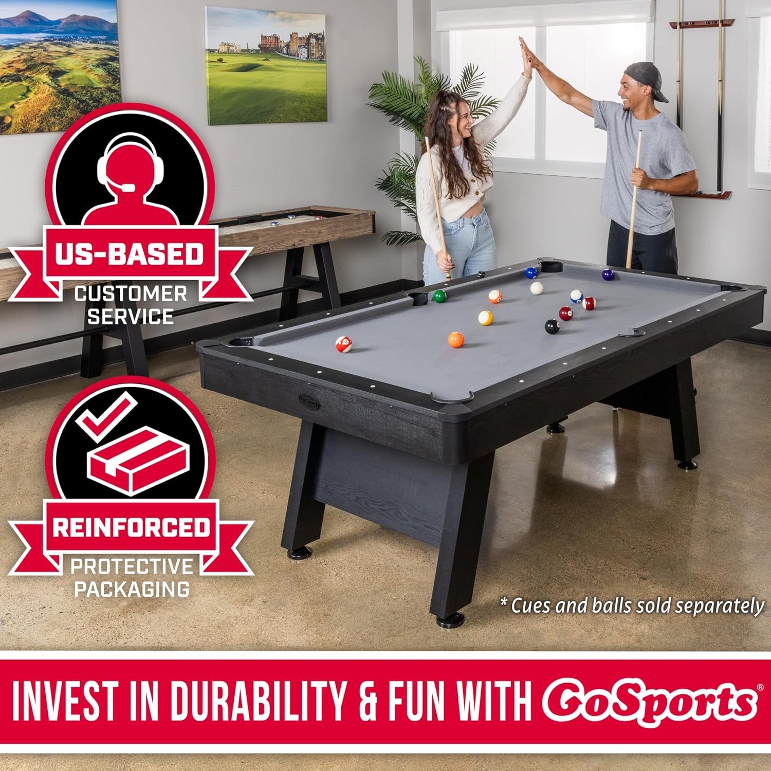 Two people high-fiving while playing on a black pool table with gray felt in a modern game room.