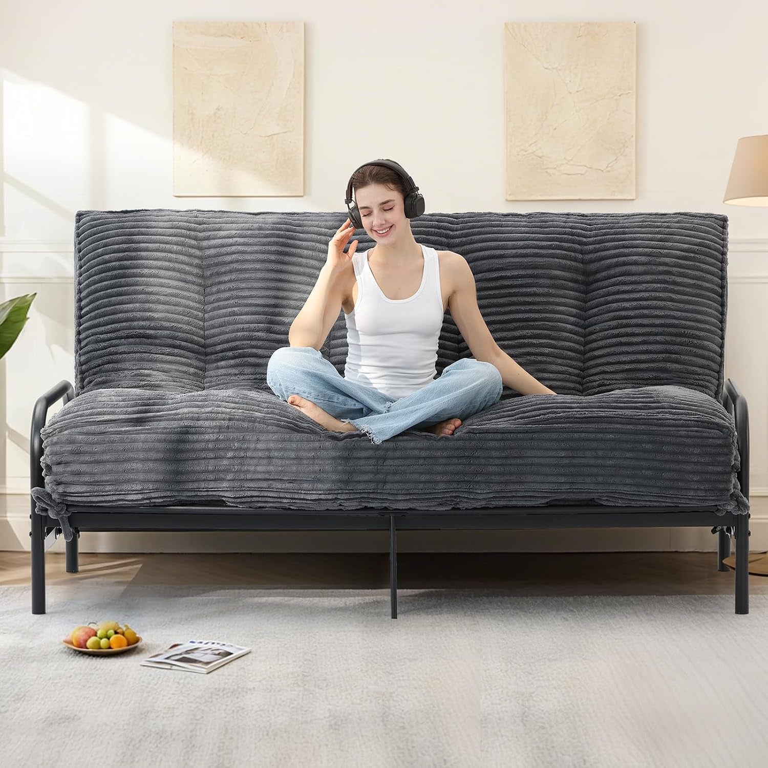 Grey ribbed faux fur futon mattress set up on a metal frame sofa with person seated