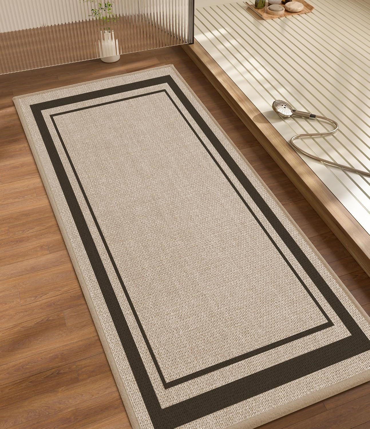 Long rectangular bath runner with double border pattern laid beside a raised bathtub on wood flooring