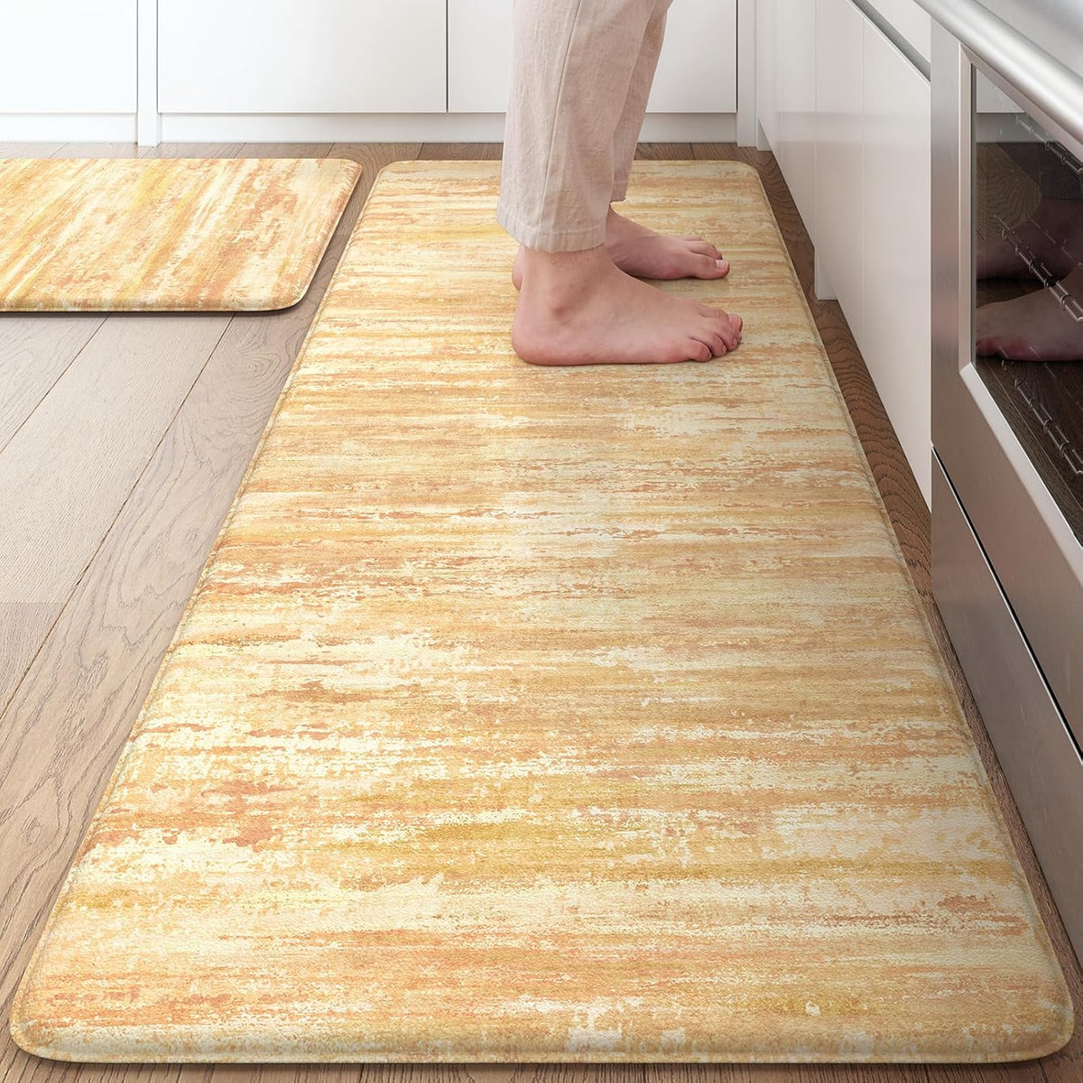 Close view of a warm golden-yellow textured kitchen mat with a person standing on it.