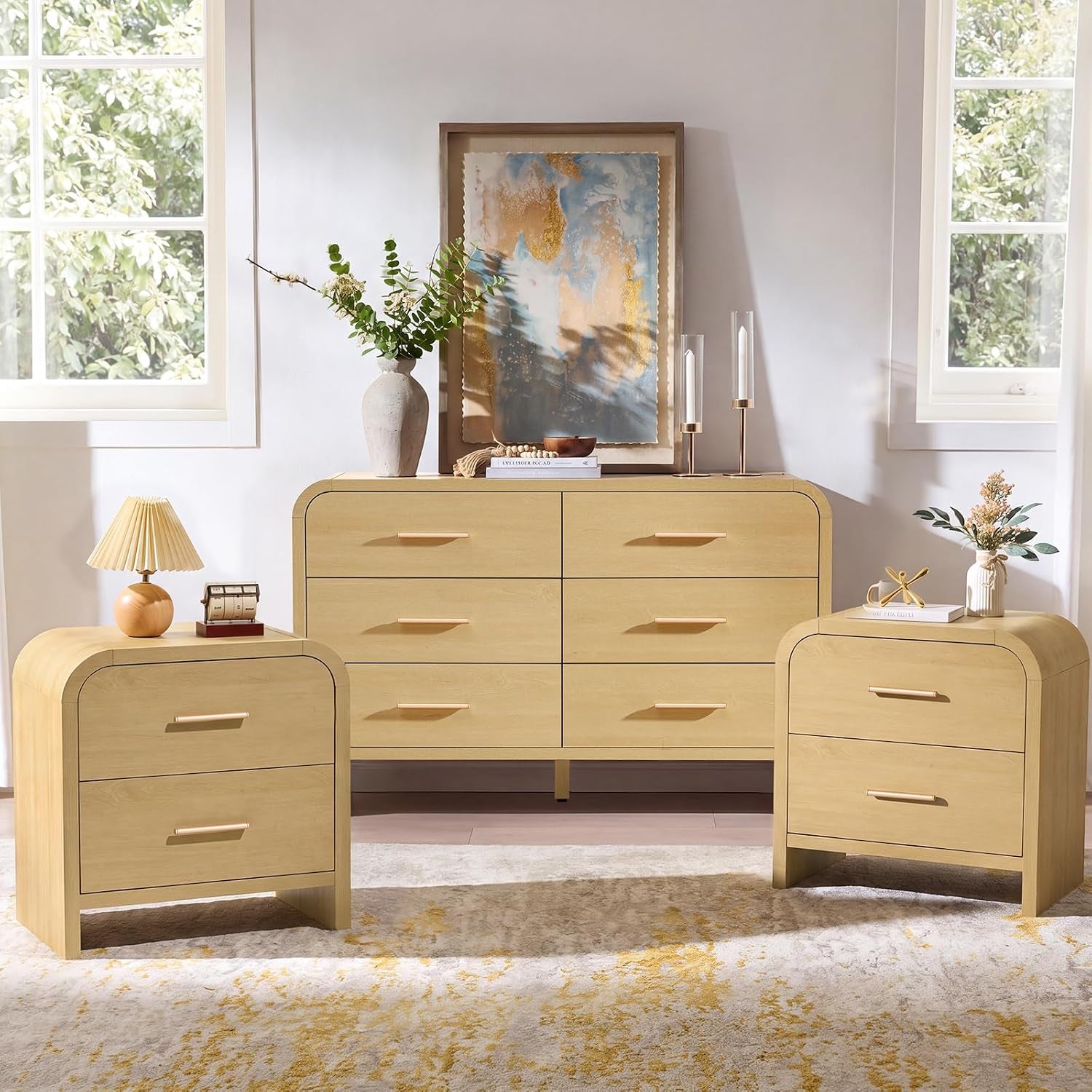 Low frontal shot of light wood dresser and two nightstands highlighting rounded corners and slim bar handles.