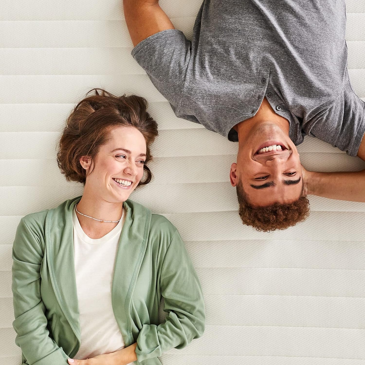 Overhead view of two people lying side-by-side on the mattress demonstrating surface area and support.