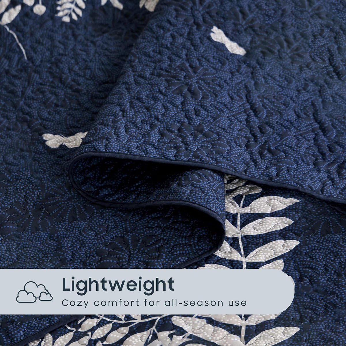 Textured close-up of navy quilt showing dense quilting, visible stitch pattern and white floral detail