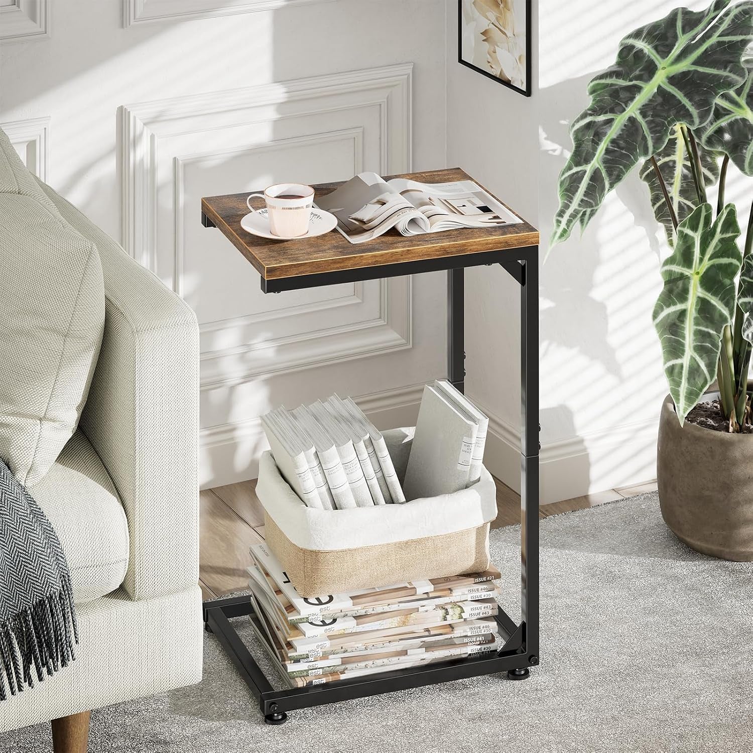 Slim C-shaped end table beside a light sofa holding a cup and magazines in a living room setting
