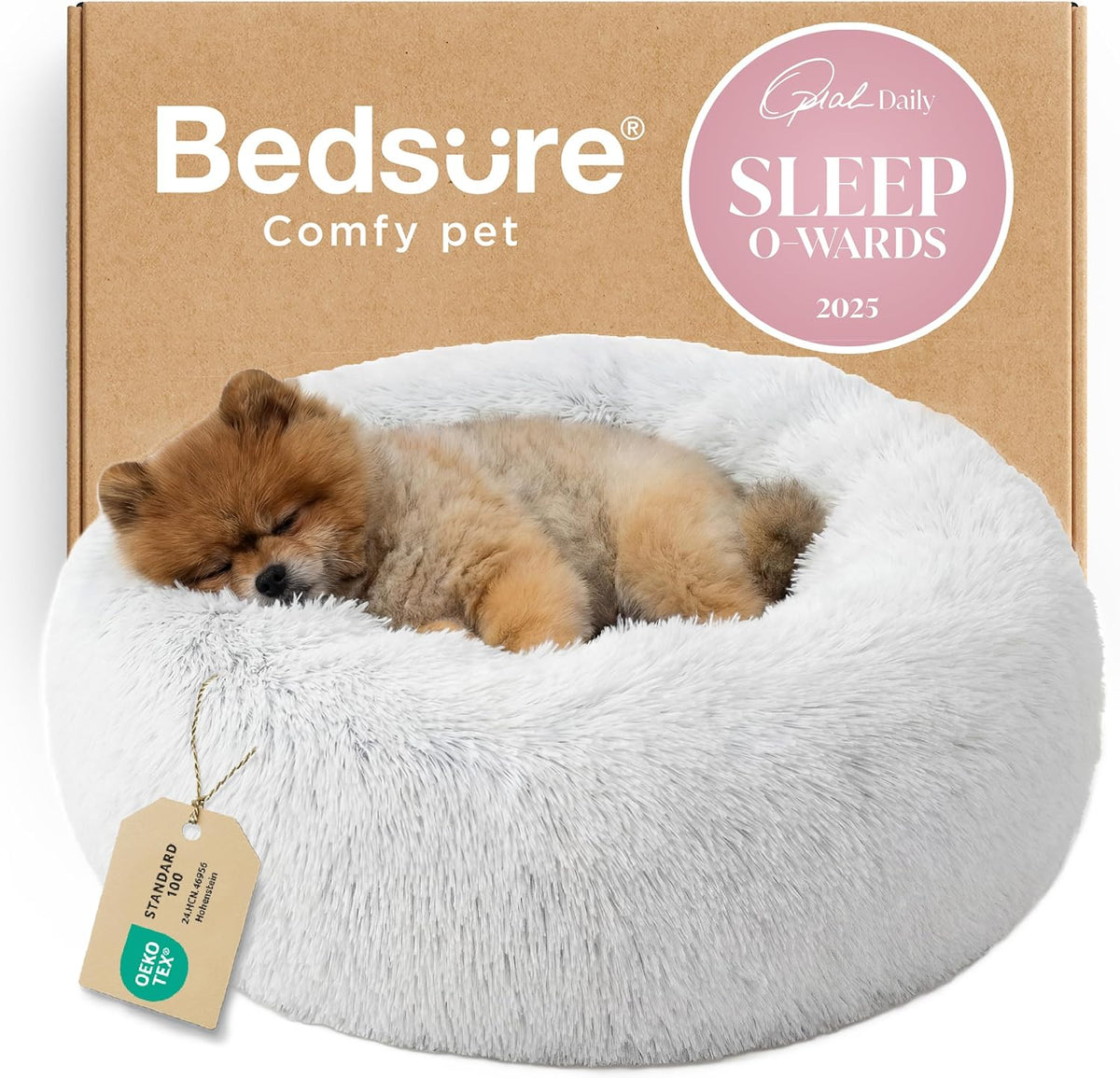 Front view of a white fluffy donut bed with a small brown puppy sleeping on its side and packaging behind