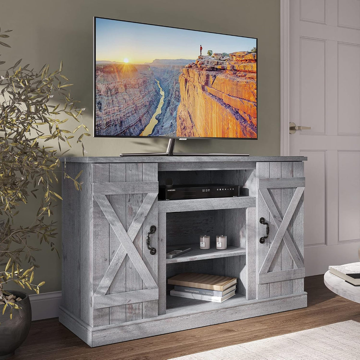 Graywashed finish TV stand shown in a room with X-panel doors, black decorative handles and styled shelves.