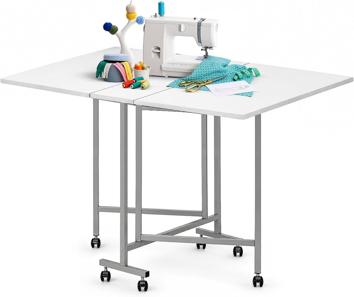 Three-panel white work surface with sewing supplies and a machine on a raised metal frame with caster wheels.