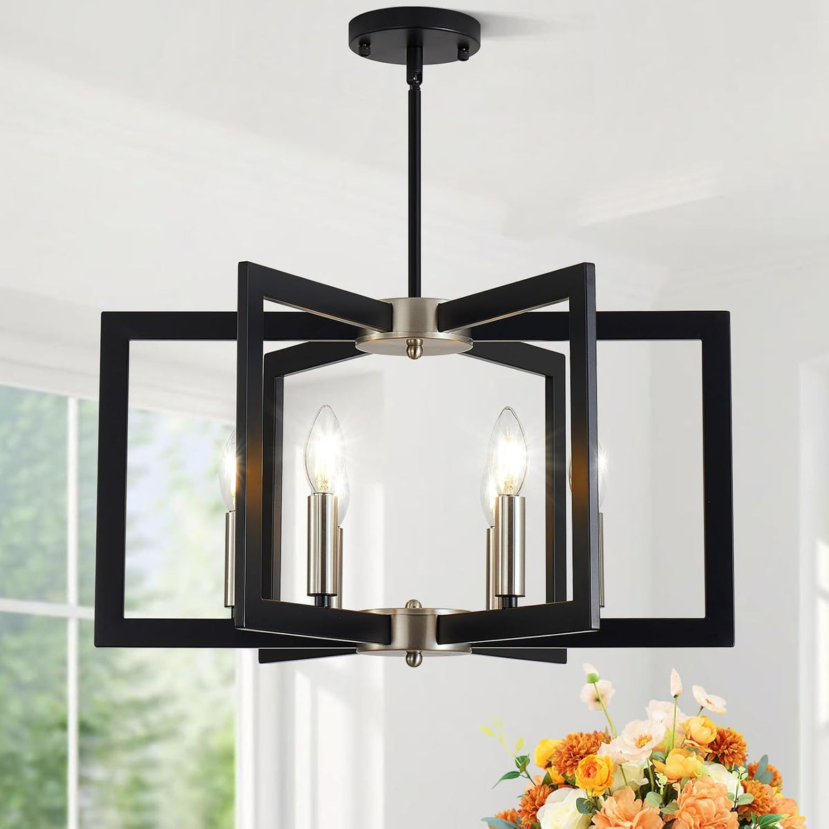 Front view of a black geometric chandelier with four candle-style bulbs hanging above a floral arrangement.