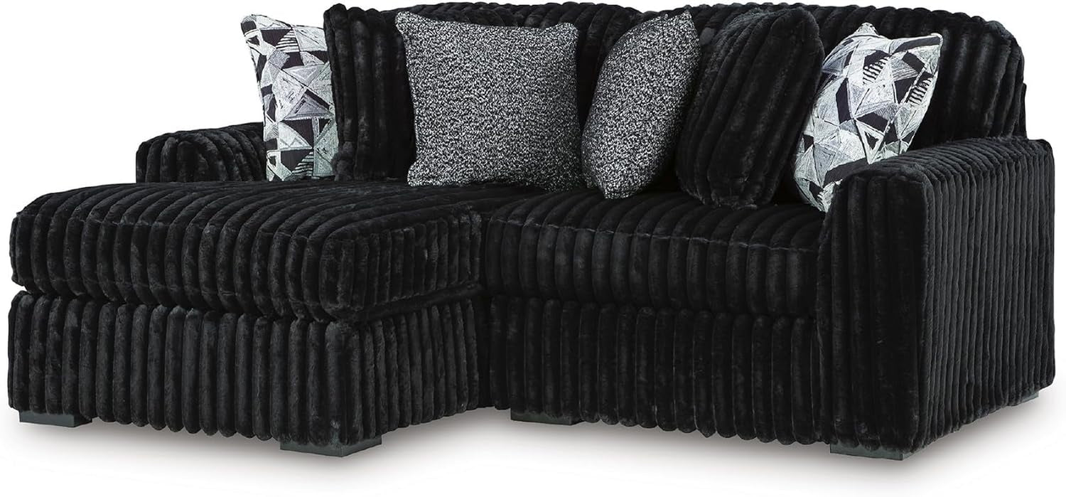 Black jumbo-corduroy sectional with a left chaise and mixed textured throw pillows.