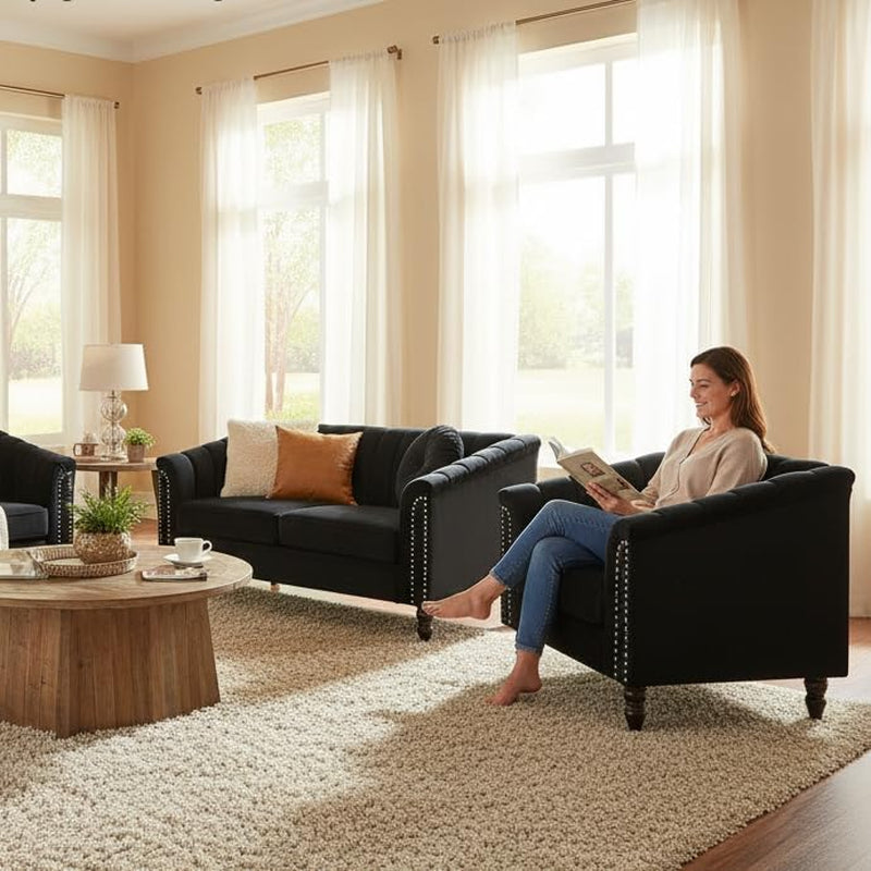 Black velvet armchair side view in a sunlit living room setting with sofa visible in the background