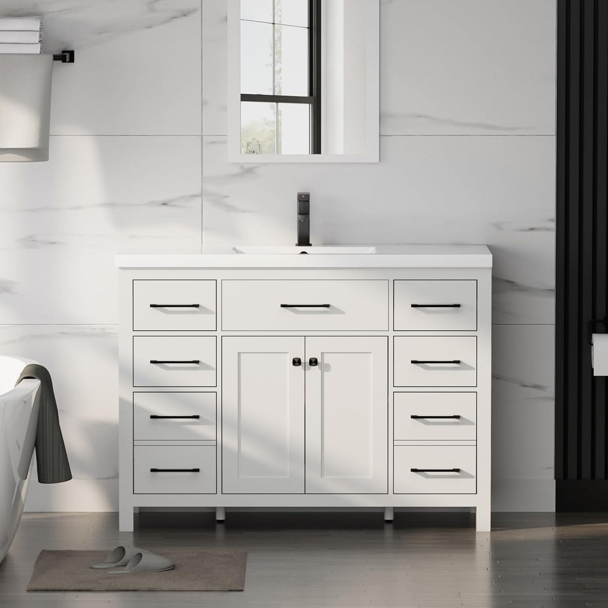 Front view of a white bathroom vanity with single sink, black handles and a bath tub at left.