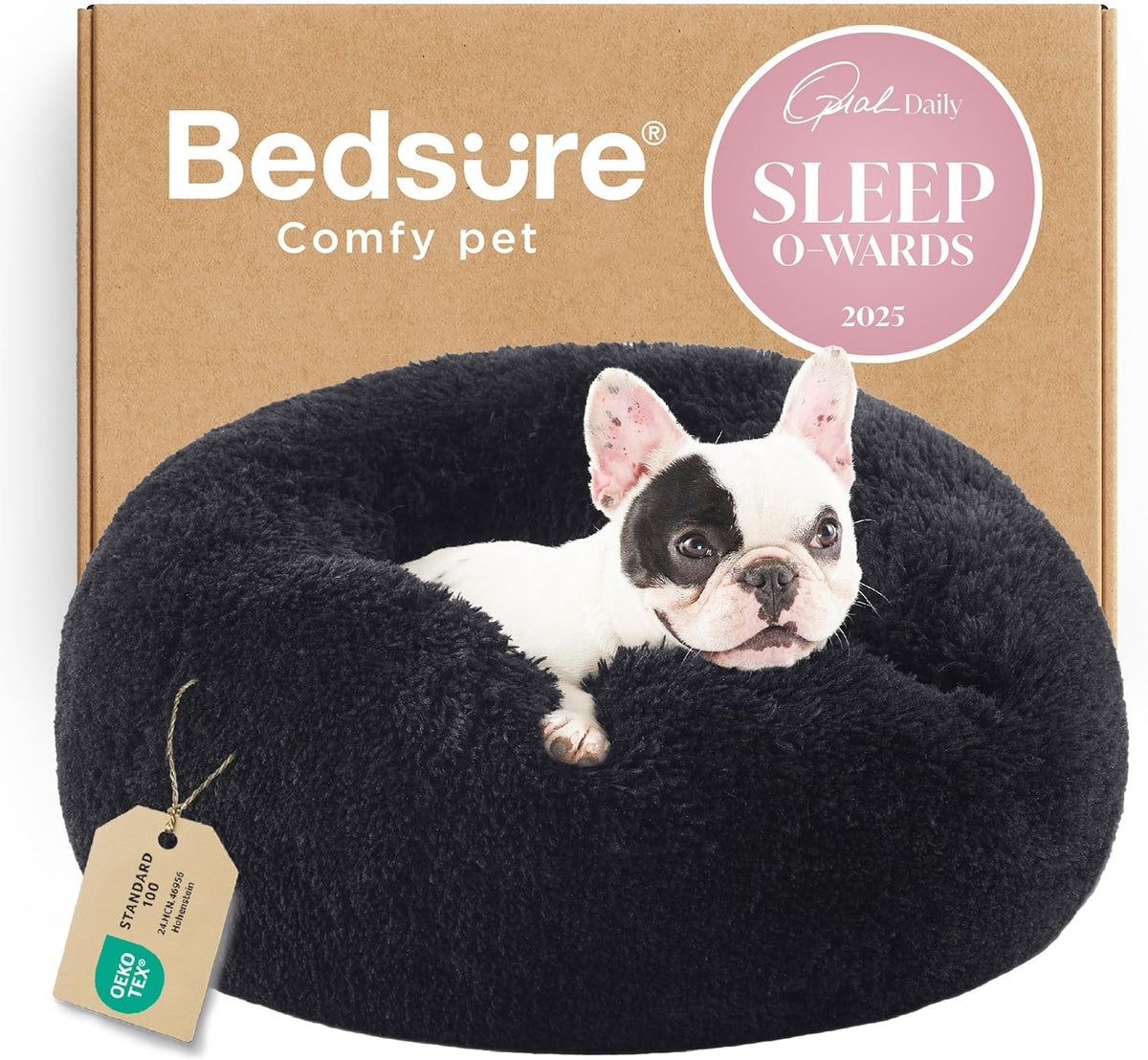 Front view of a black fluffy donut bed with a small black-and-white dog peeking over the rim and box behind