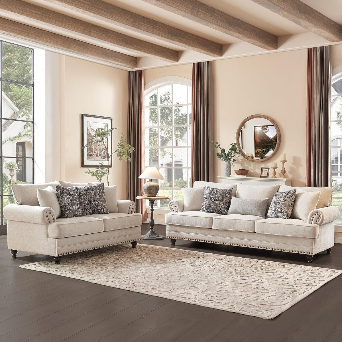 Beige paisley chenille sofa and loveseat with rolled arms and nailhead trim in a bright living room setting