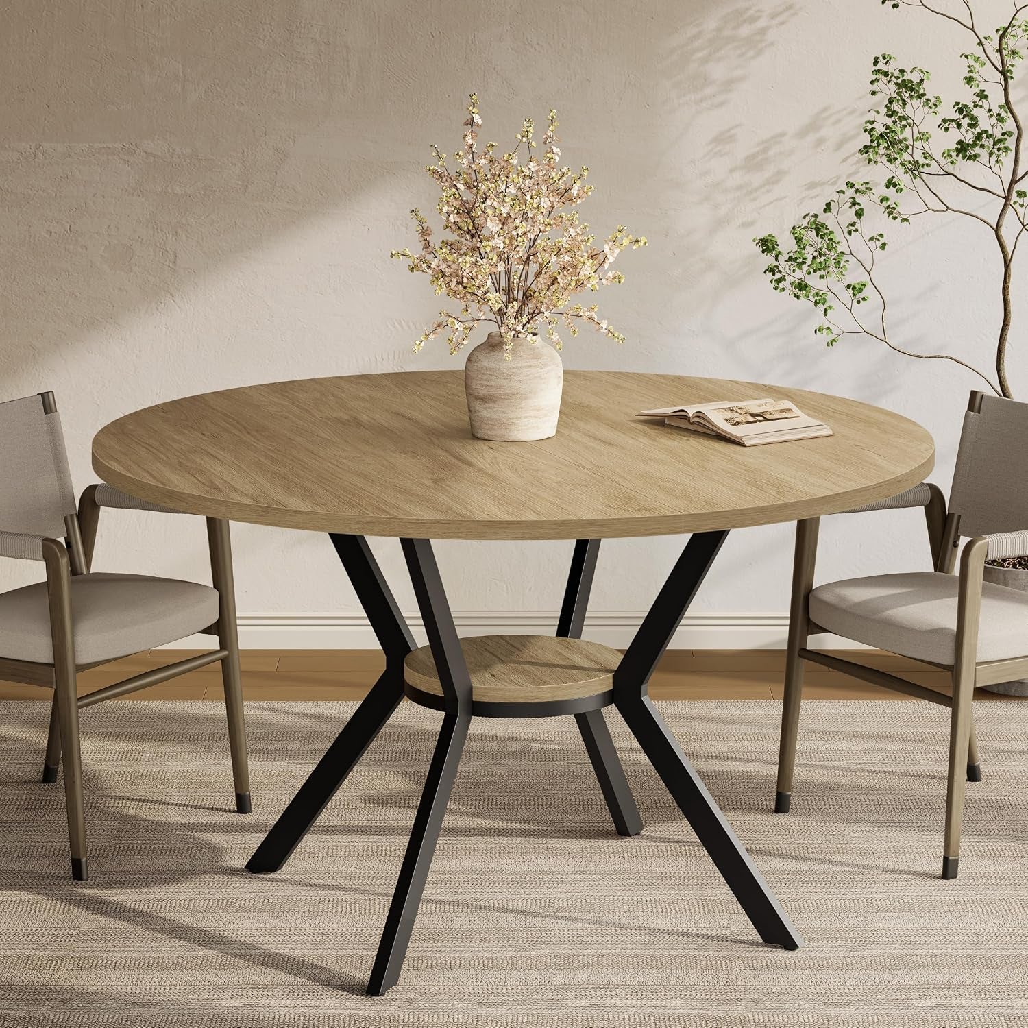 Close view of a round oak-look dining table with black angled legs and a circular lower shelf, styled with a vase.