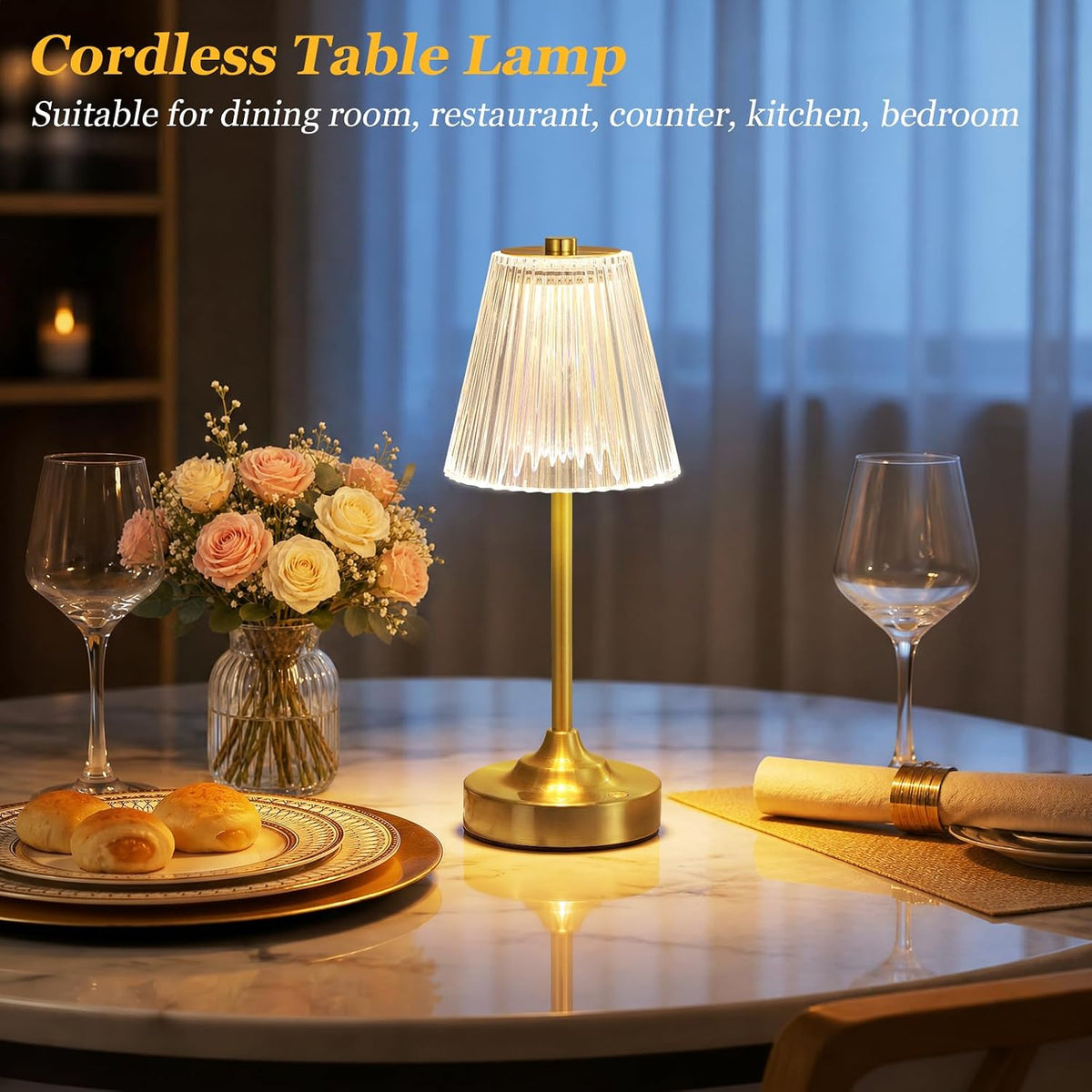Gold table lamp lit on a dining table with curtains in the background and glassware on the table