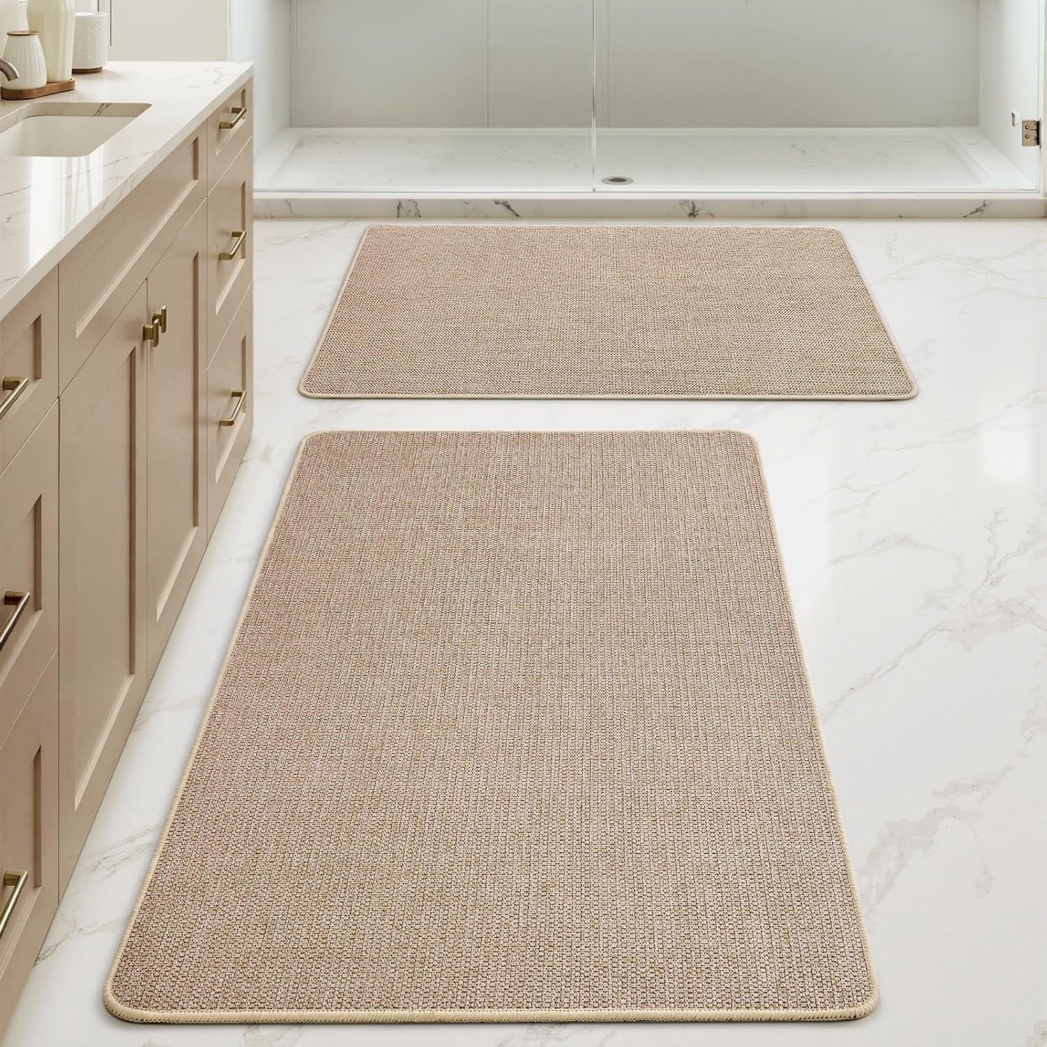 Floor-level perspective focusing on a large beige runner in foreground and a smaller matching mat near the shower.