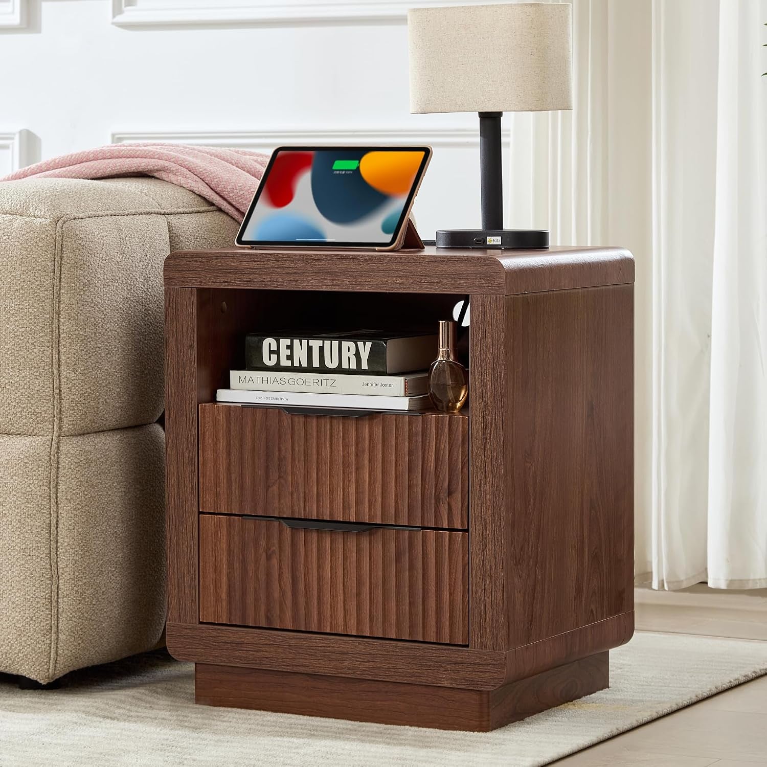 Walnut finish fluted nightstand beside sofa showing open shelf and two drawers, angled front view