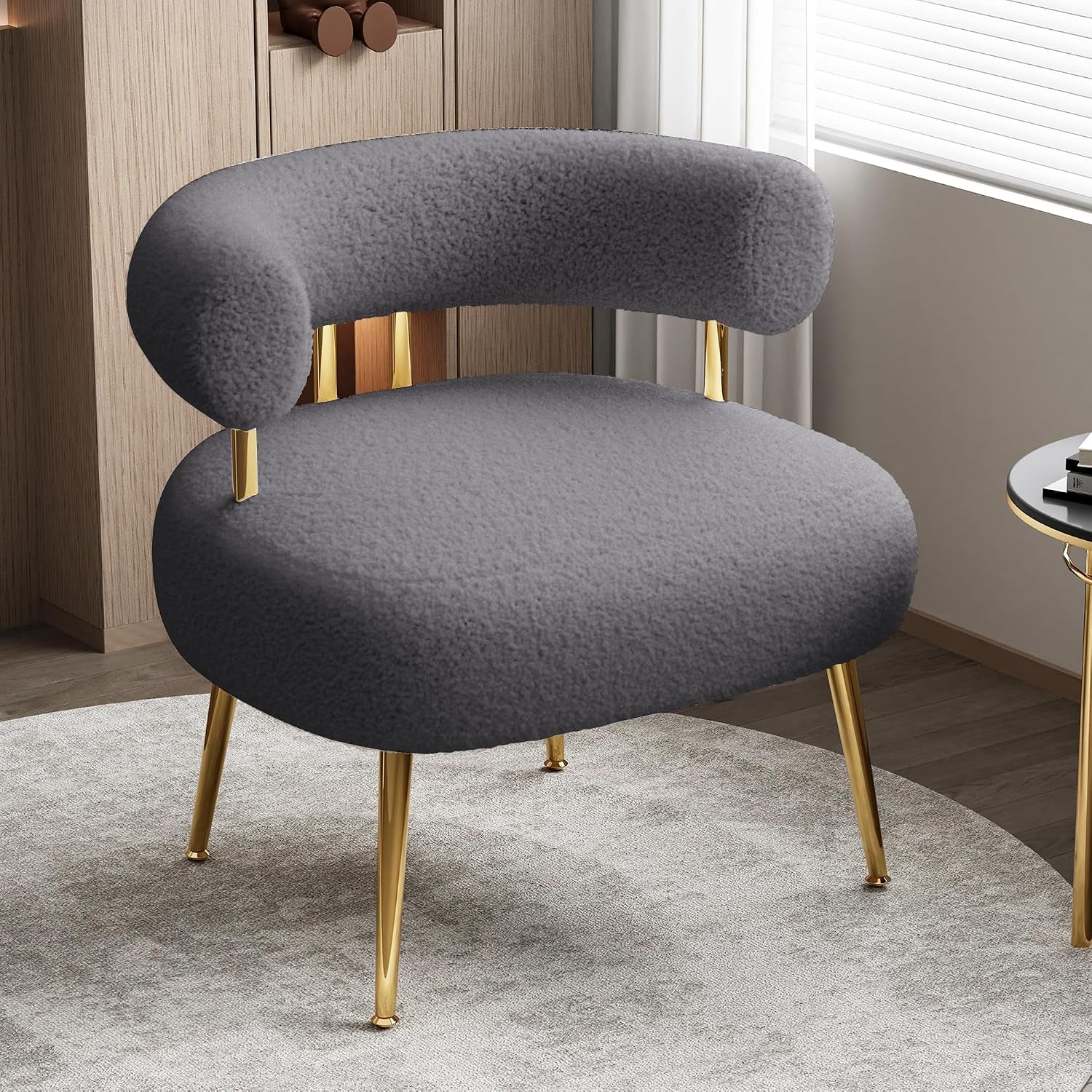 Gray rounded barrel accent chair with gold legs placed on a light rug by a window
