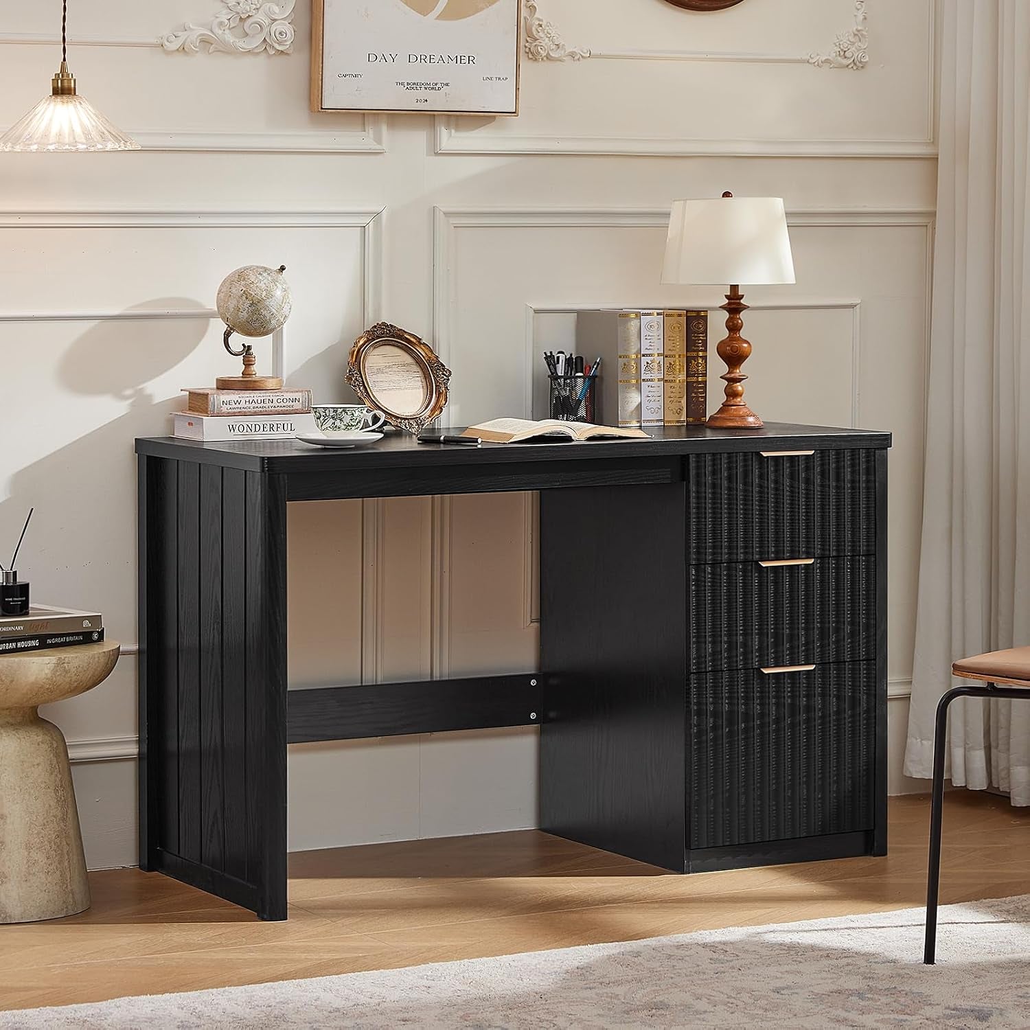 Black wood desk featuring three textured fluted drawers and a simple rectangular top in a neutral room.