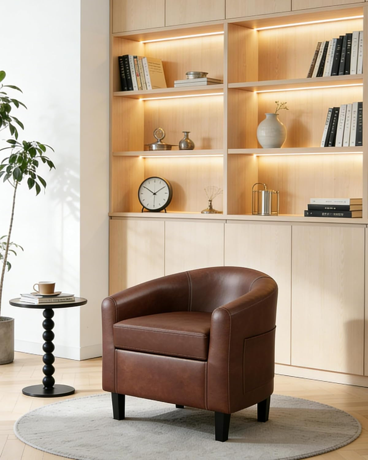 Single brown barrel armchair on a round rug beside a small side table and built-in shelving.