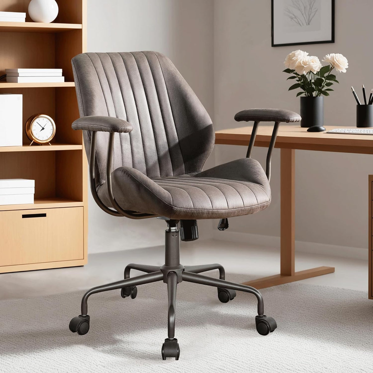 Muted gray-brown chair centered under soft light showing vertical stitching and padded arms