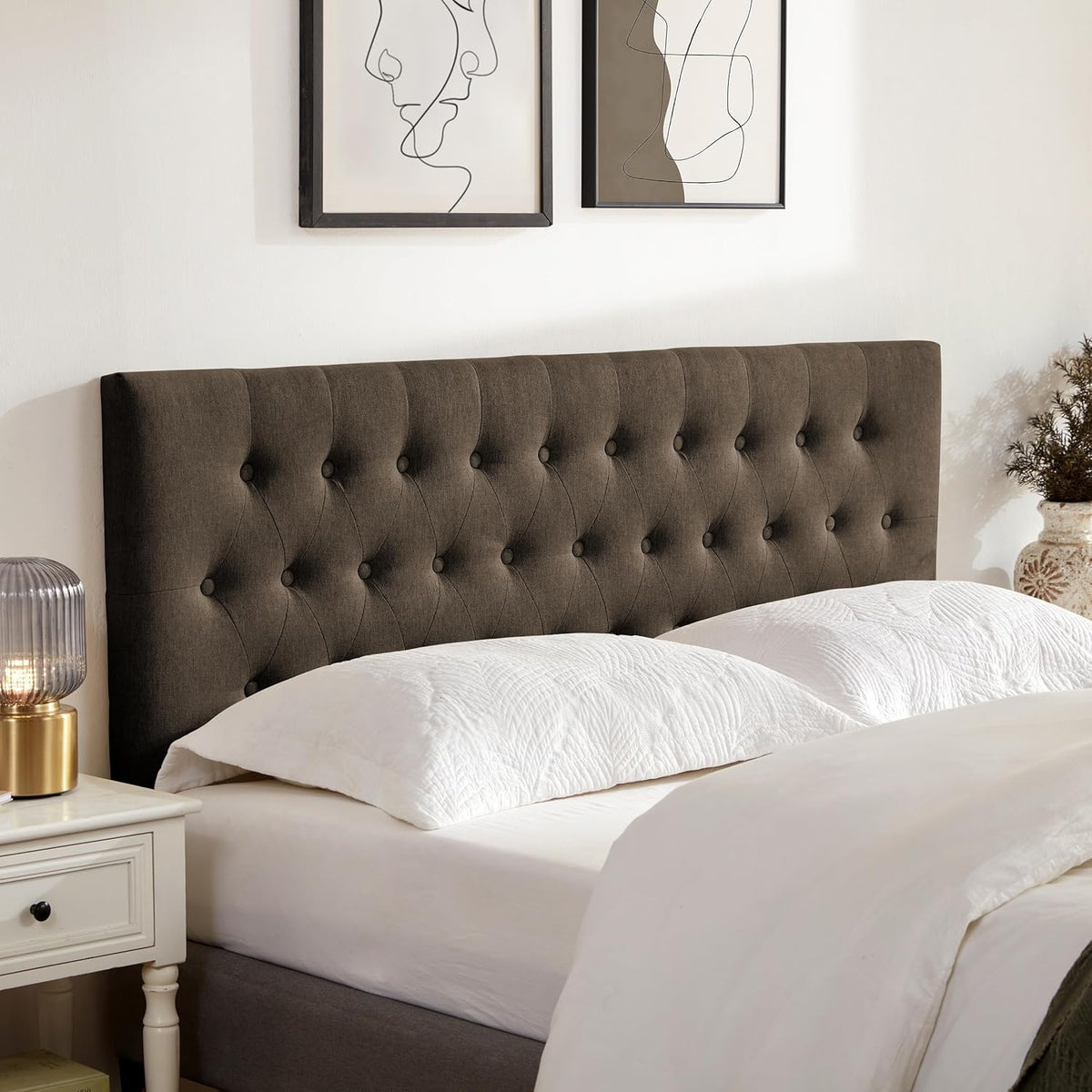 Warm dark brown tufted headboard viewed at an angle with decorative vase and lamp nearby.