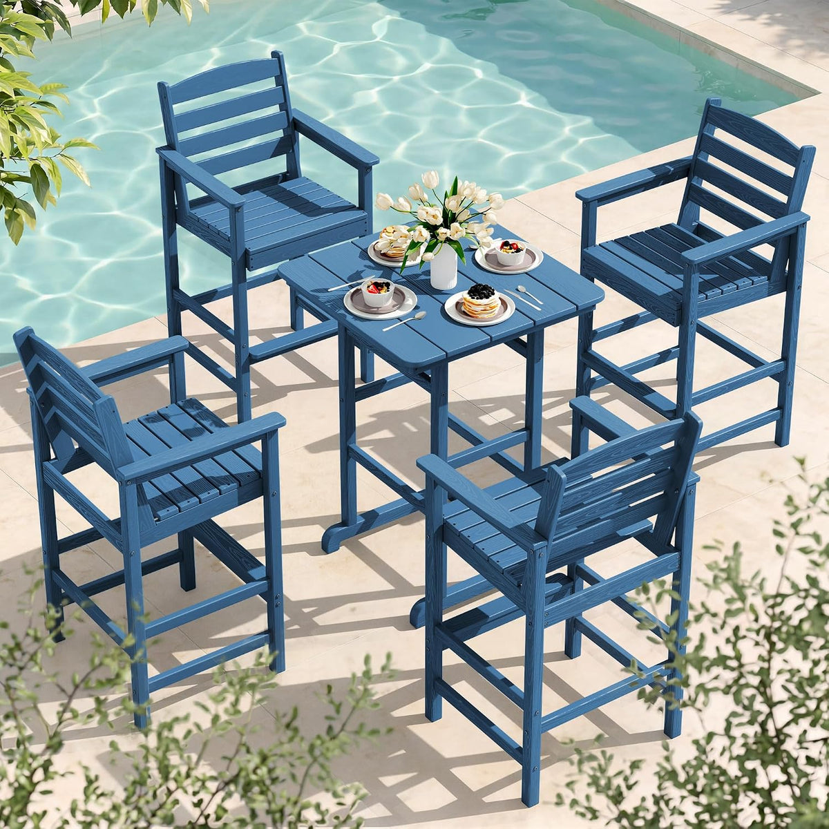 Blue bar-height Adirondack table and four matching chairs set beside a pool, plates on the table.