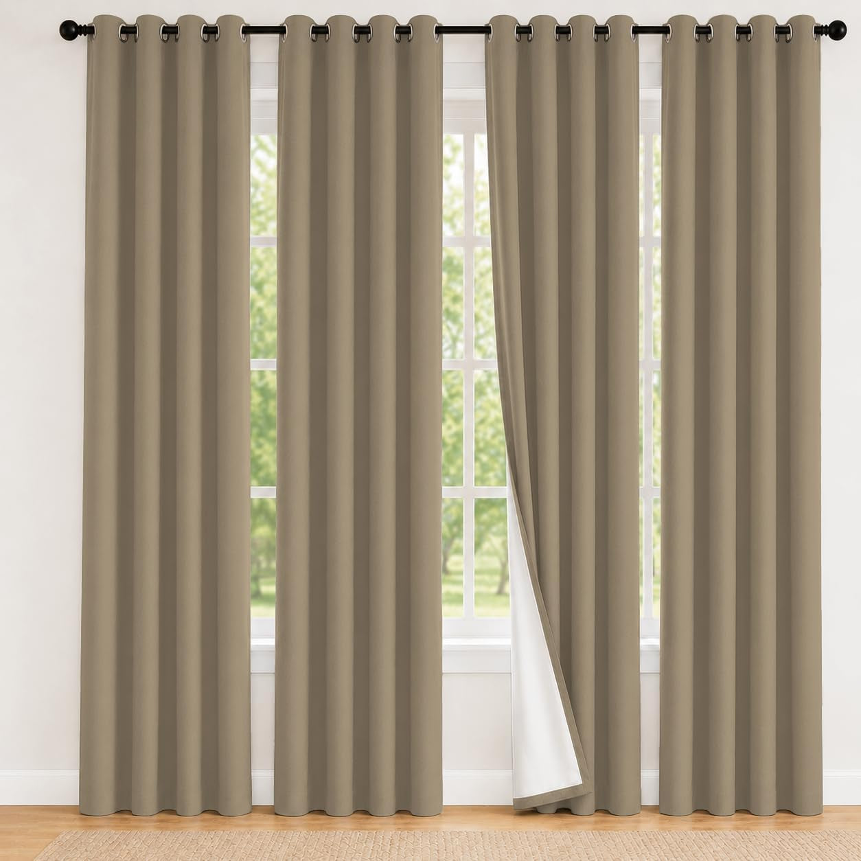 Two wide taupe curtain panels covering a large window, one edge turned to show white backing.