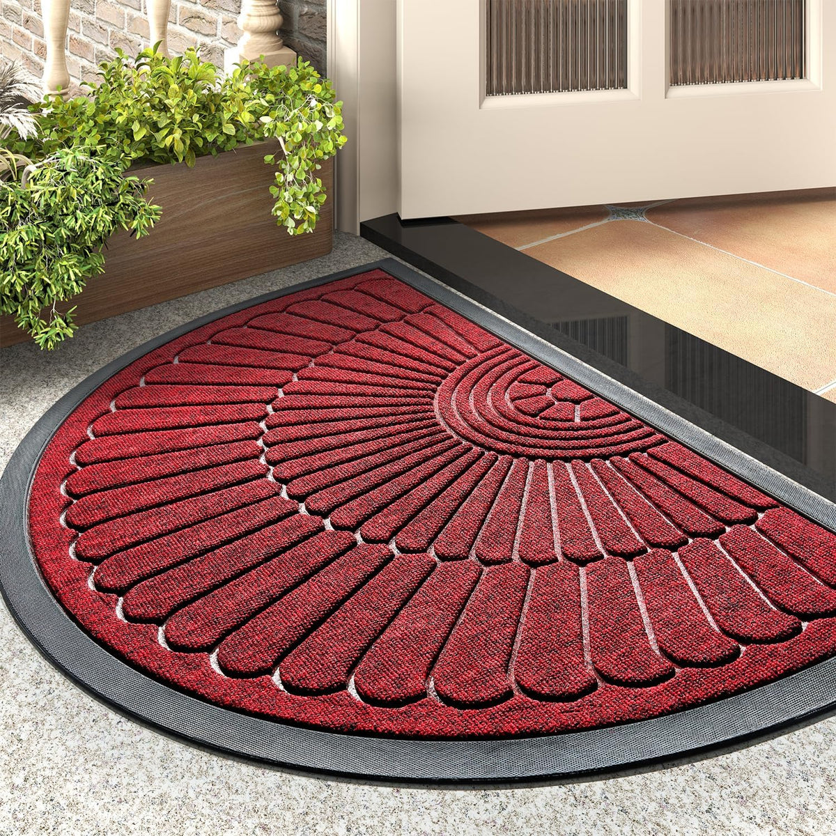 Close angled view of a red semicircular mat at a doorstep showing radiating textured ribs and a rubber rim.
