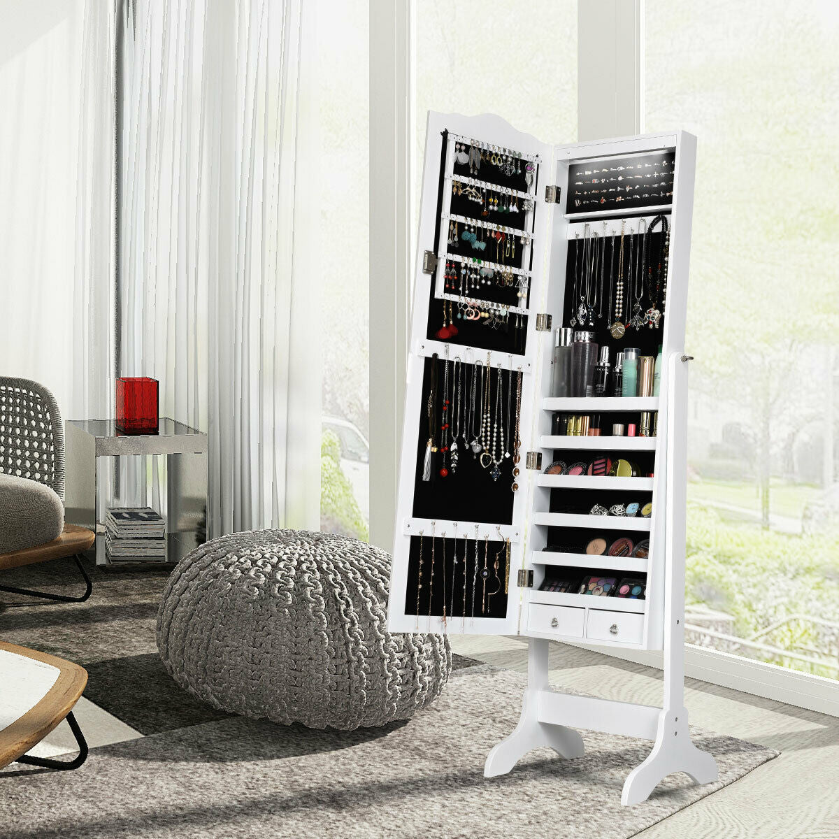White jewelry armoire standing open beside a window, with jewelry and small accessories arranged inside.