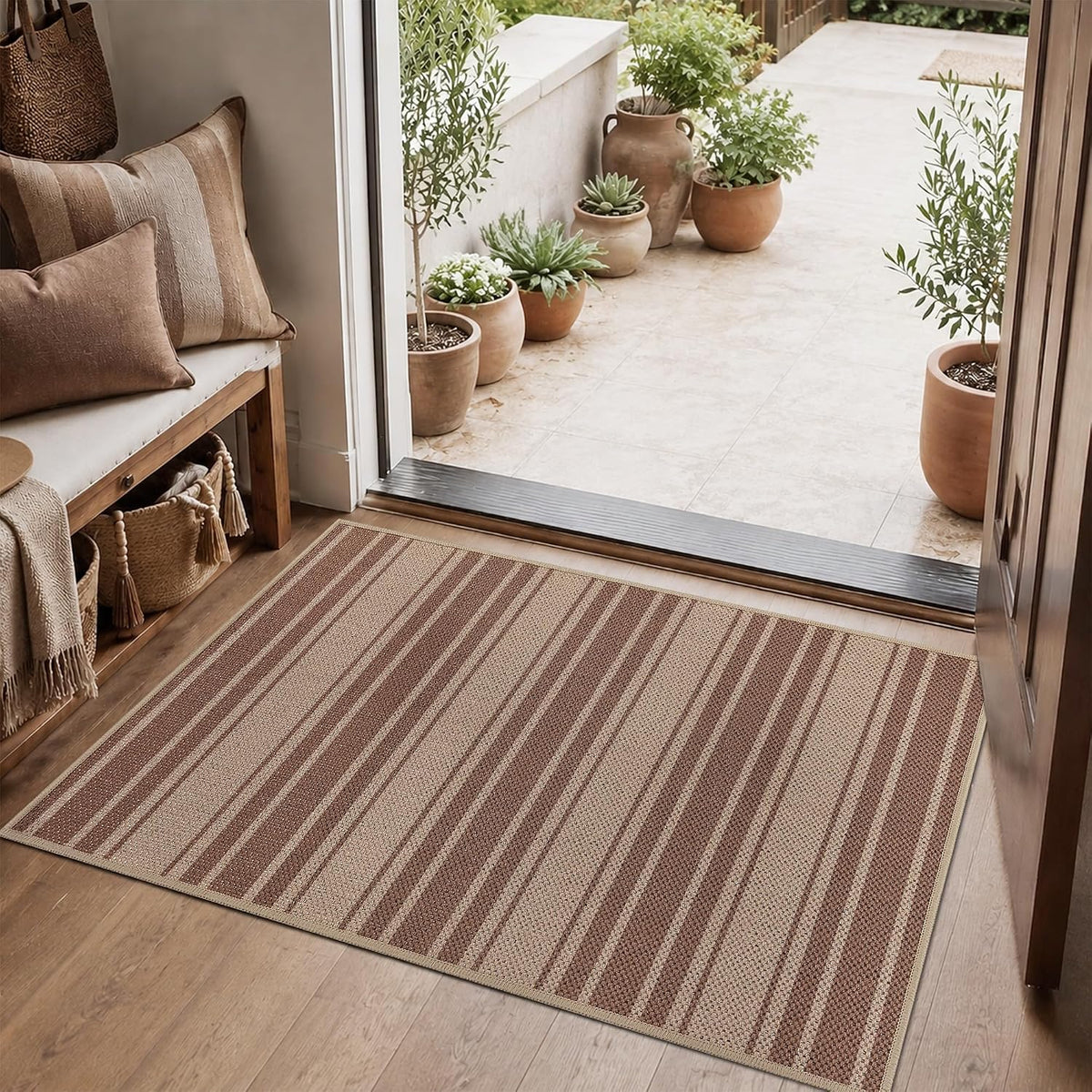 Small striped mat at a sliding door threshold surrounded by potted plants and a bench with cushions.
