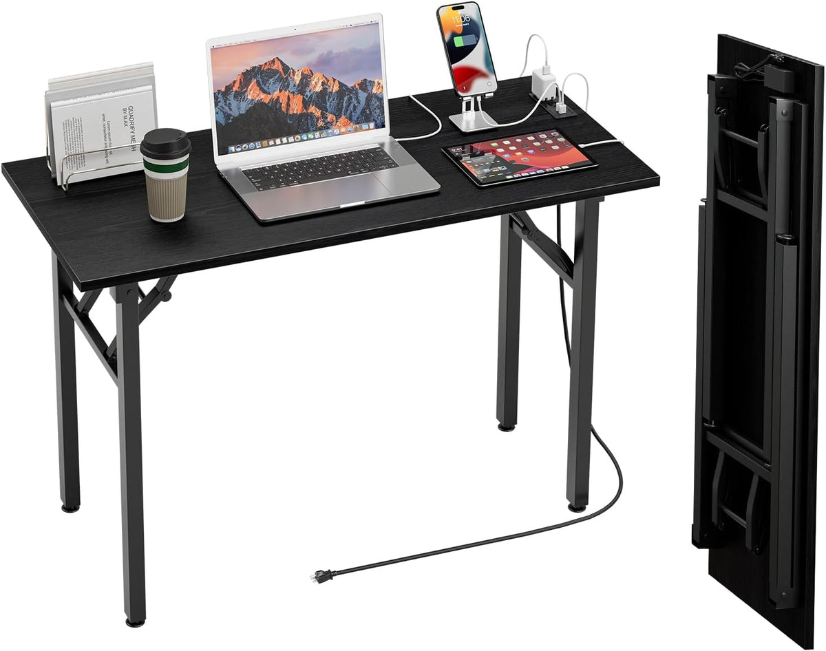 Black tabletop desk shown set up with laptop, tablet and phone charger; folded tabletop panel shown upright at right