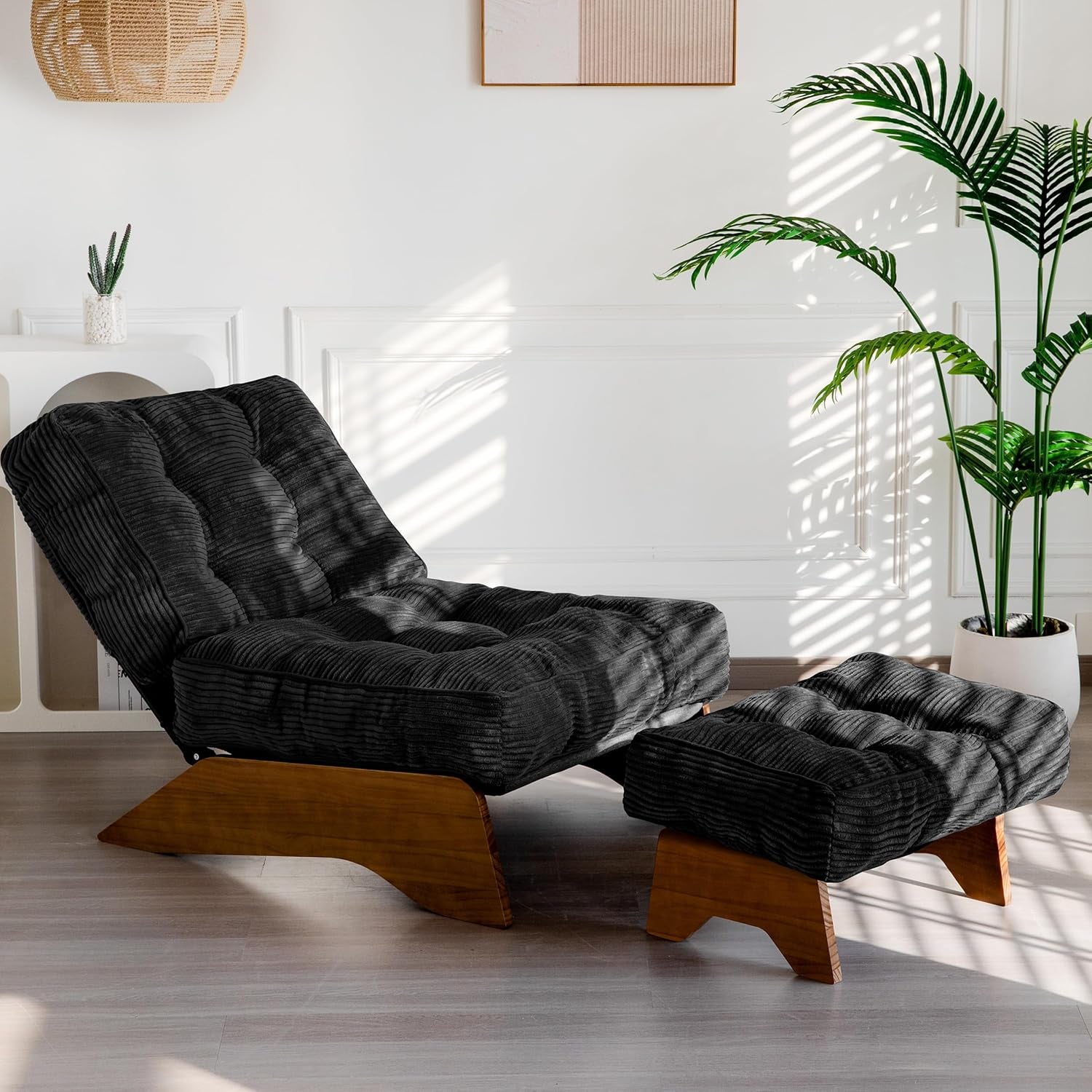Black corded fabric tufted lounge chair with matching ottoman set against a white paneled wall.