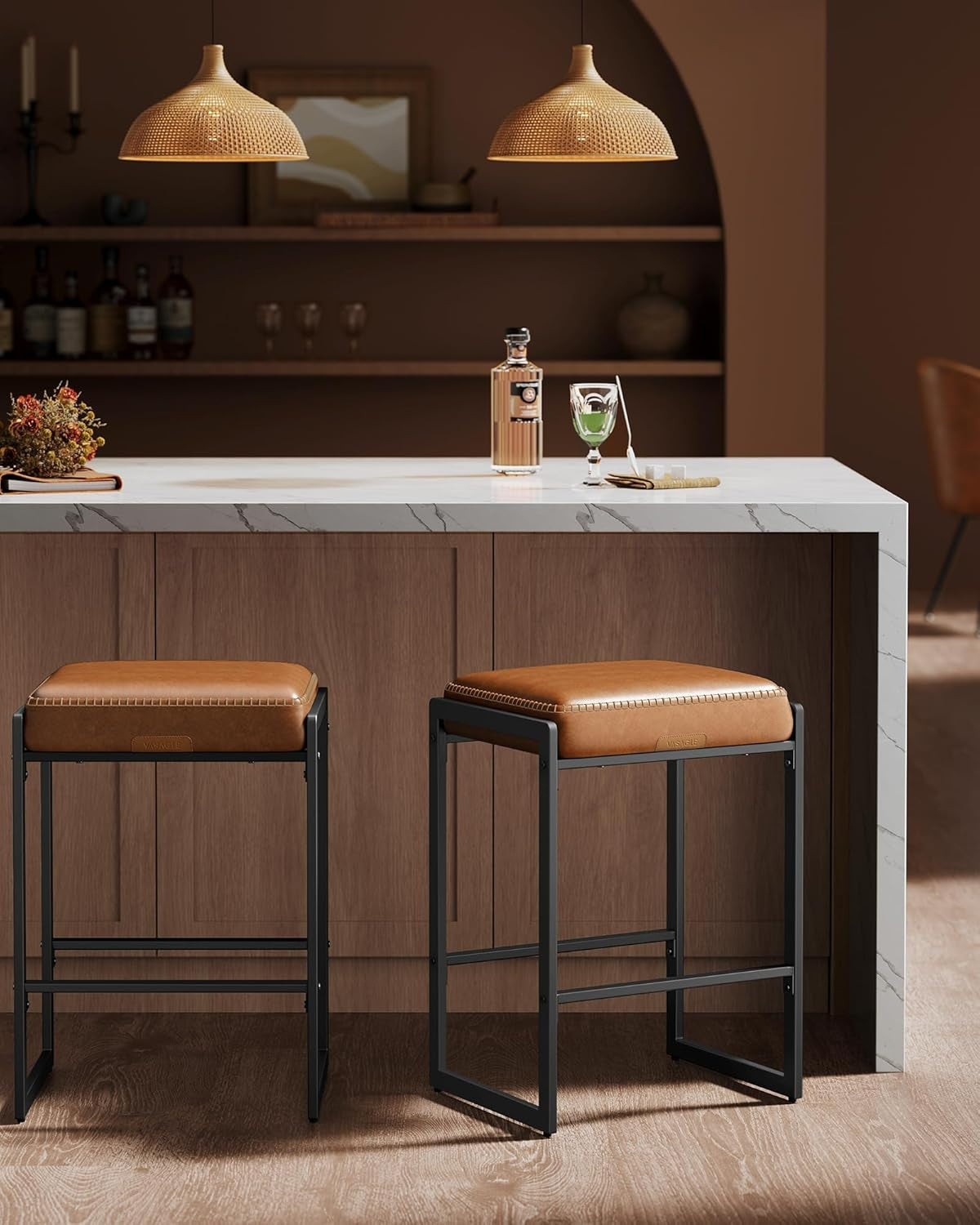 Two backless caramel-cushioned counter stools with black rectangular metal frames, one slightly pulled out beneath a