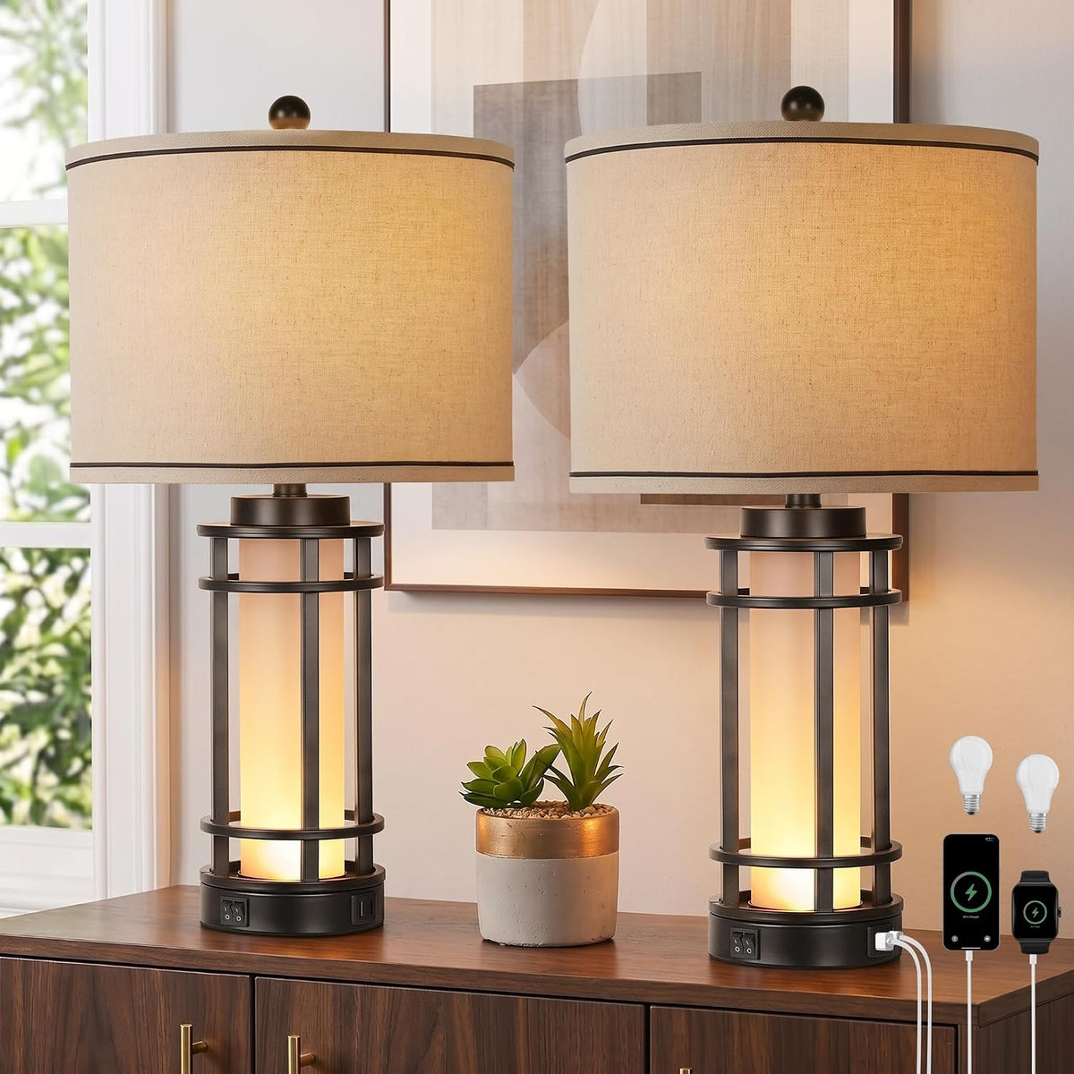 Close-up of two linen-style drum shades and metal-base accents on matching table lamps displayed on a wooden surface.