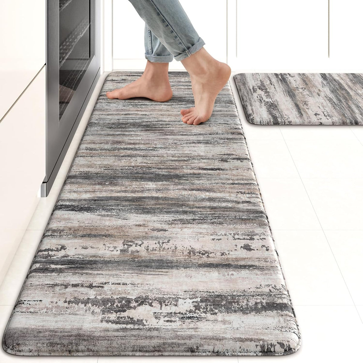 Close perspective of a gray‑tone cushioned runner with bare feet stepping along it and a second matching mat nearby.