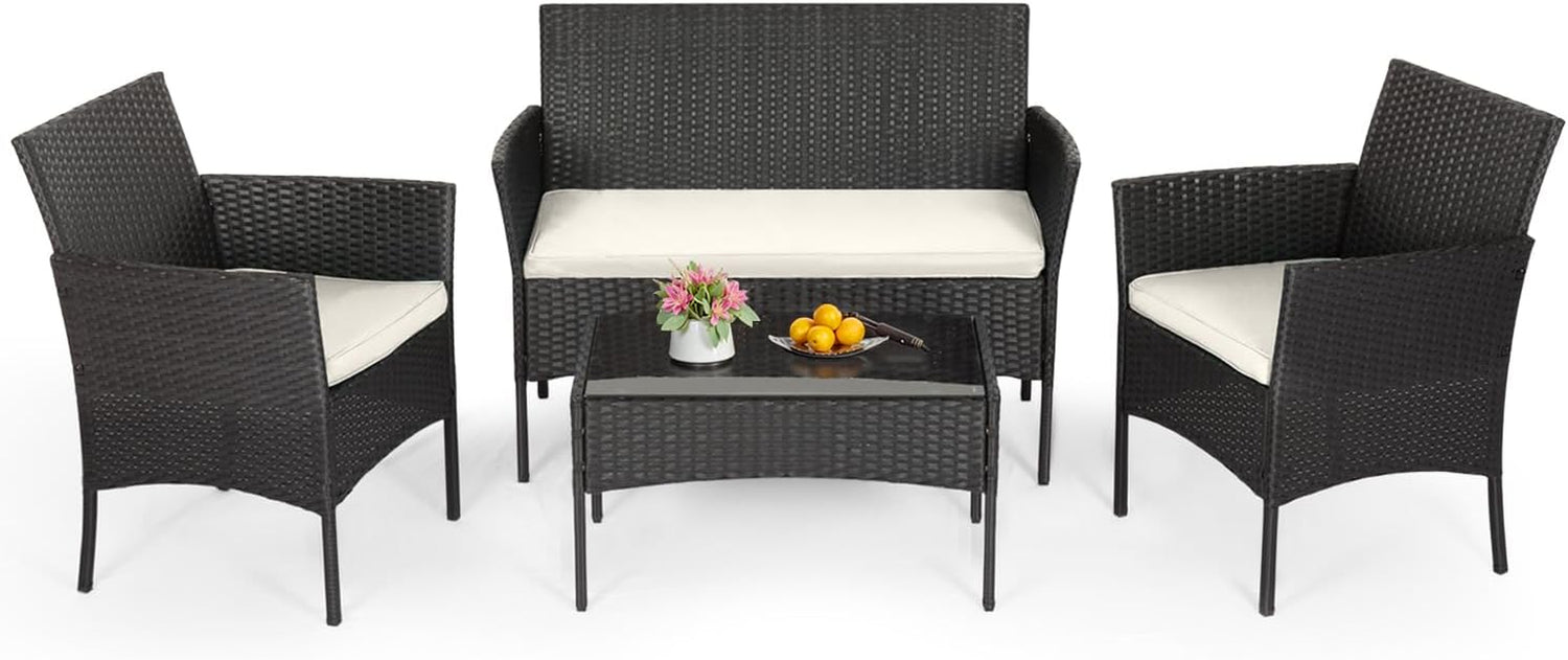 Four-piece outdoor rattan conversation set with loveseat, two armchairs and glass-top coffee table on white background