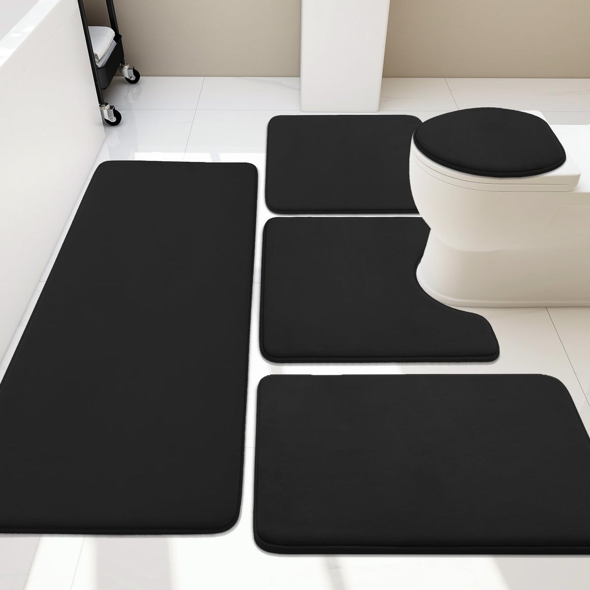 Black memory-foam bath rugs placed on glossy white tile floor beside a toilet and tub
