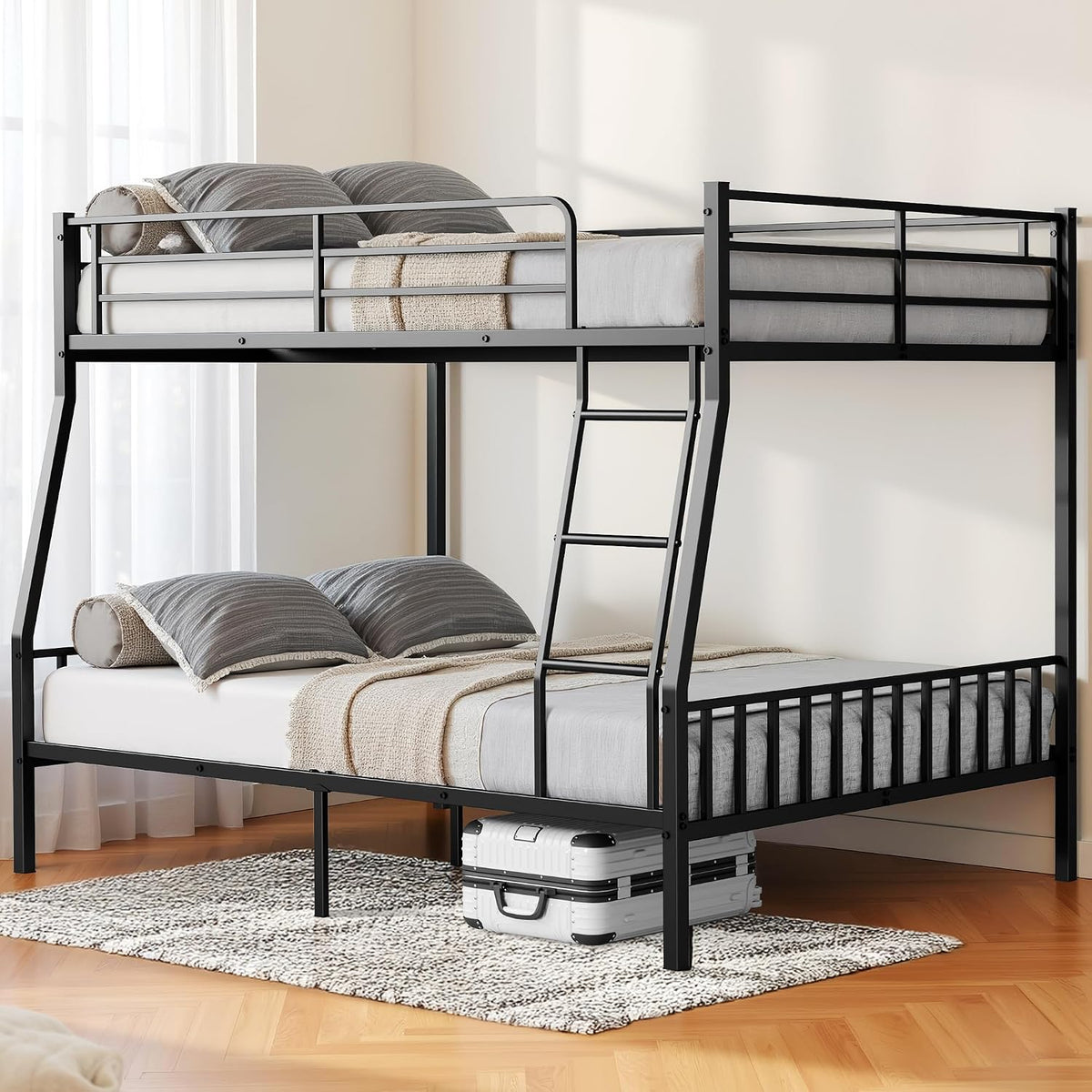Angled detail of the black metal bunk frame and ladder with neutral bedding, a rug, and a suitcase stored under the lower