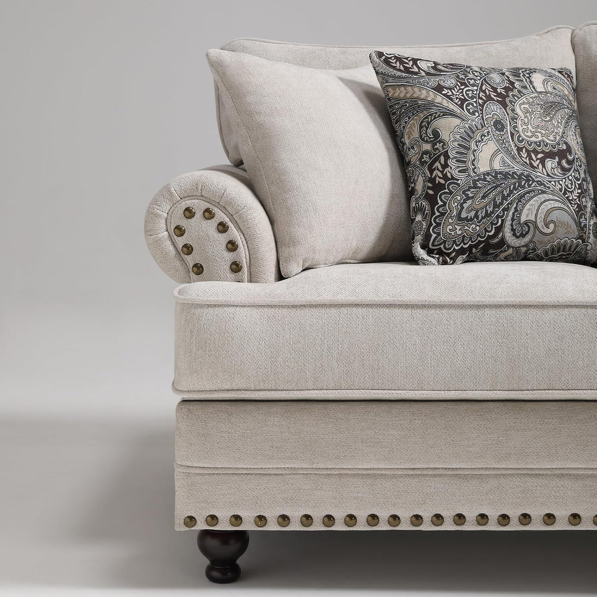 Side three-quarter view of the loveseat seat and rolled arm with paisley accent pillow and nailhead trim
