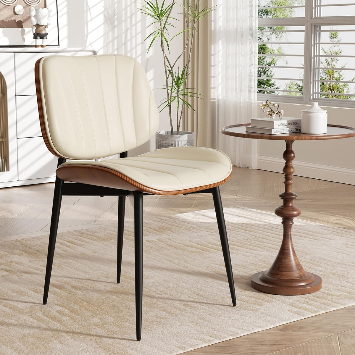 Cream faux-leather dining chair with walnut bentwood trim and black metal legs beside a round wooden side table.