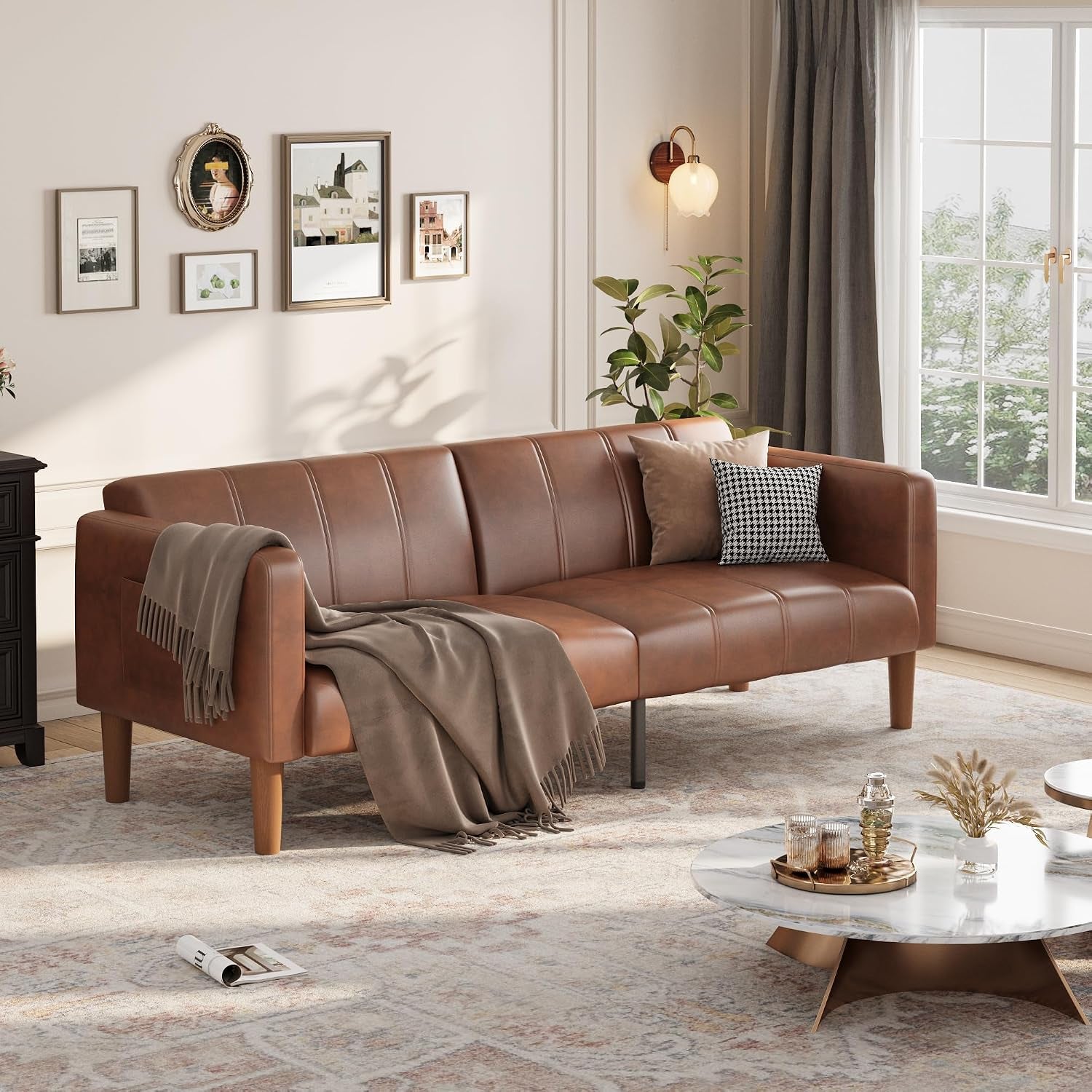 Brown PU faux leather futon arranged with a throw on the left arm and round marble-top coffee table nearby