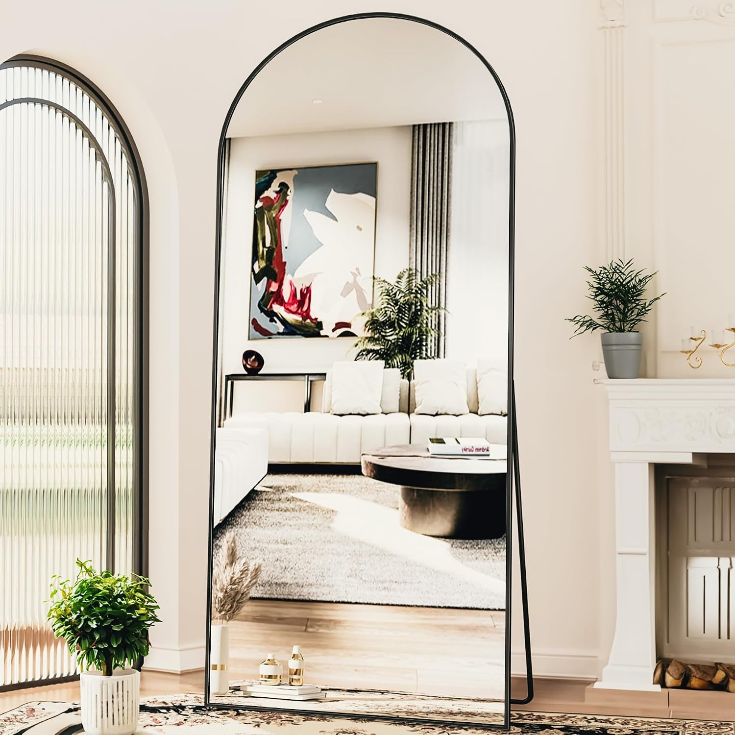 Black-framed arched full-length mirror freestanding on a floor easel reflecting a bright living room.