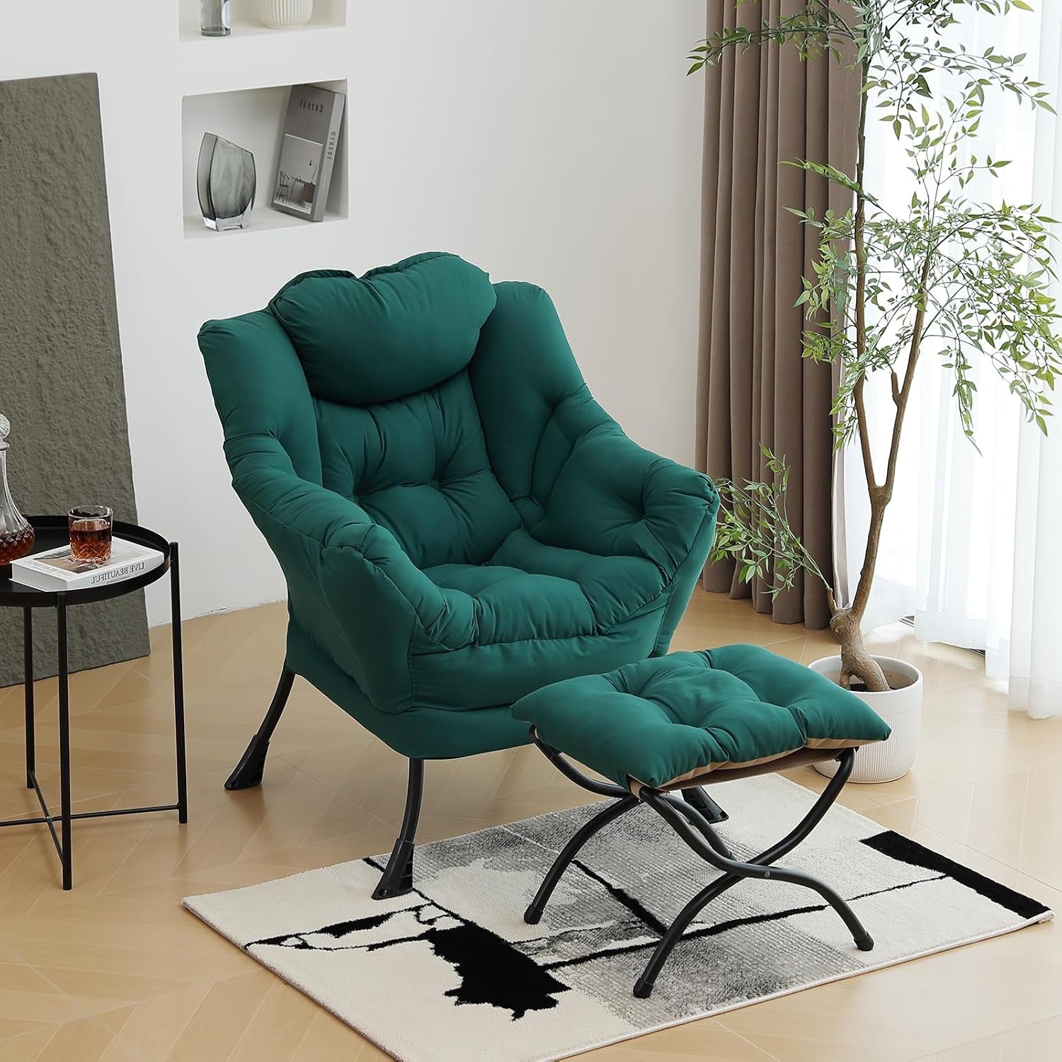 Teal cushioned lounge chair with matching ottoman on a rug beside a side table and potted plant in a bright room.