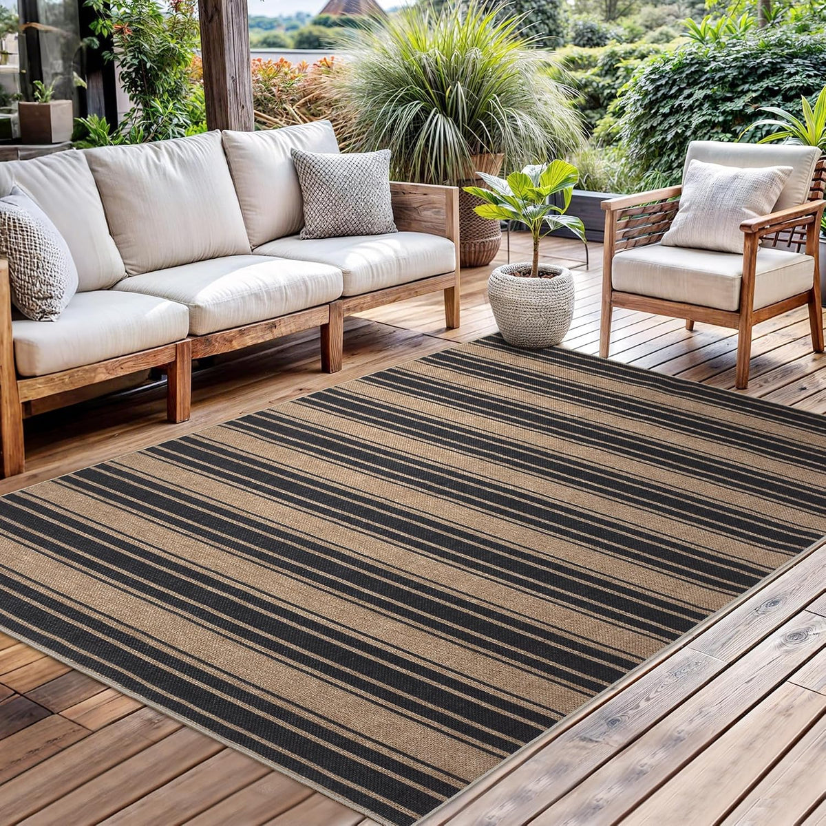 Striped outdoor rug on a wooden deck beneath a cushioned sofa and a potted plant in a garden setting.