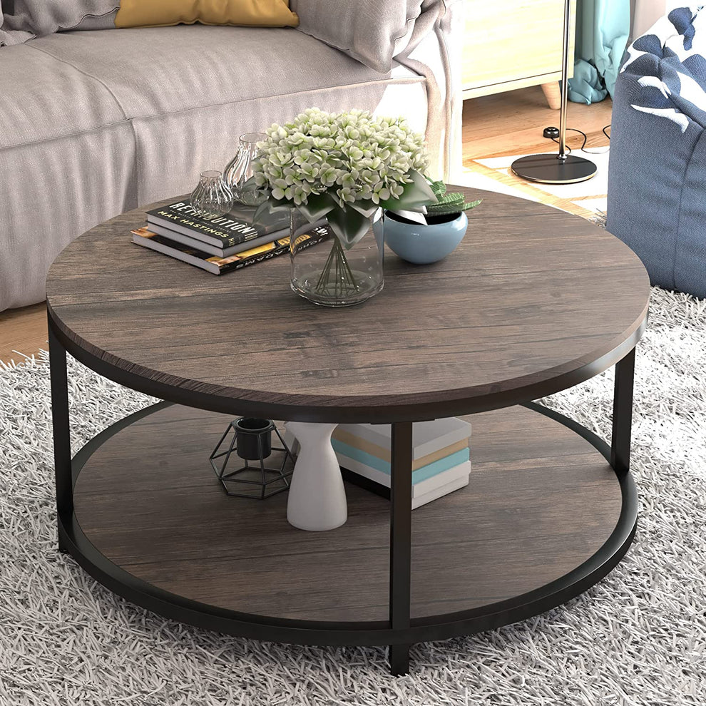 Round two-tier coffee table in light walnut finish shown angled with decorative books and vase on top