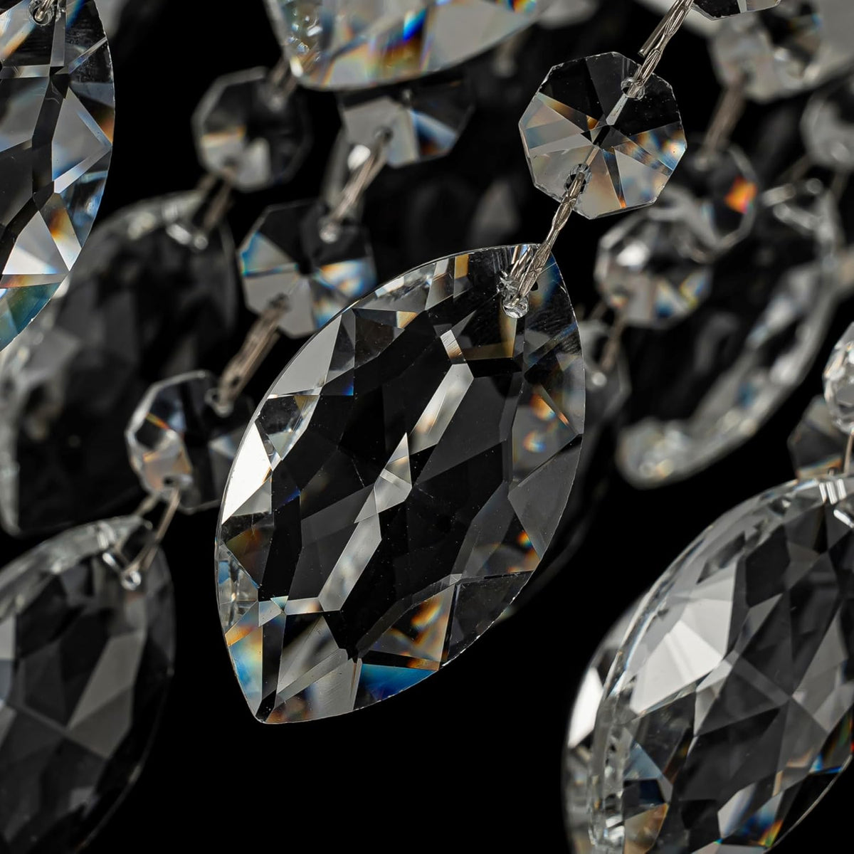 Macro close-up of faceted K9 crystal pendants showing teardrop shapes and reflective facets against a dark background.