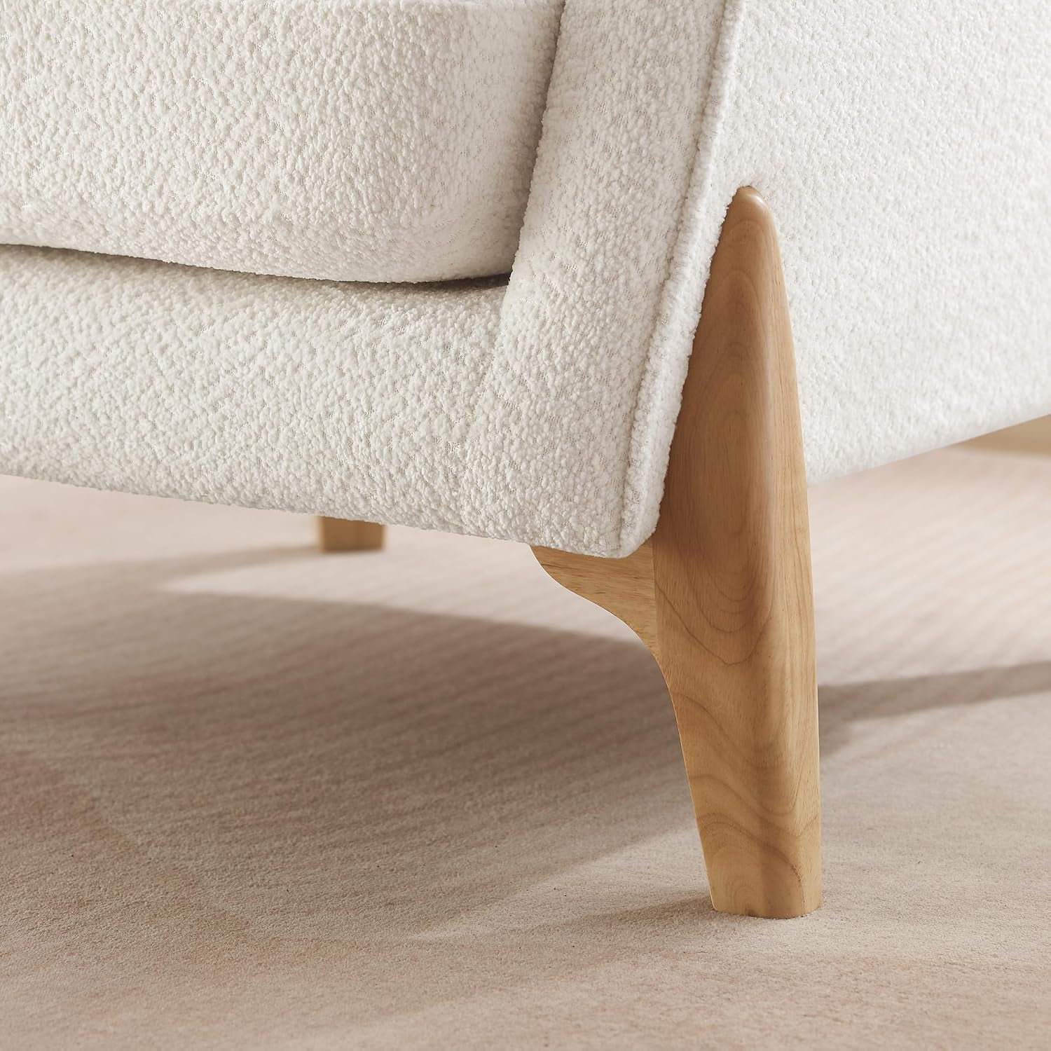 Close-up of the sculpted light wood leg and lower frame at the chair corner